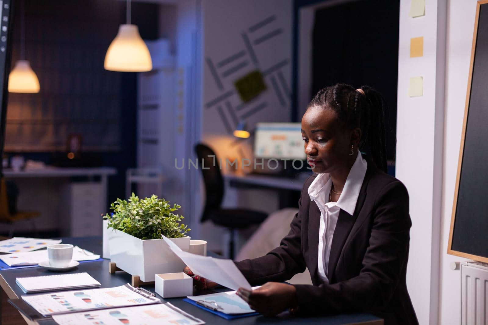 Focused workaholic african american businesswoman working at company financial charts presentation by DCStudio
