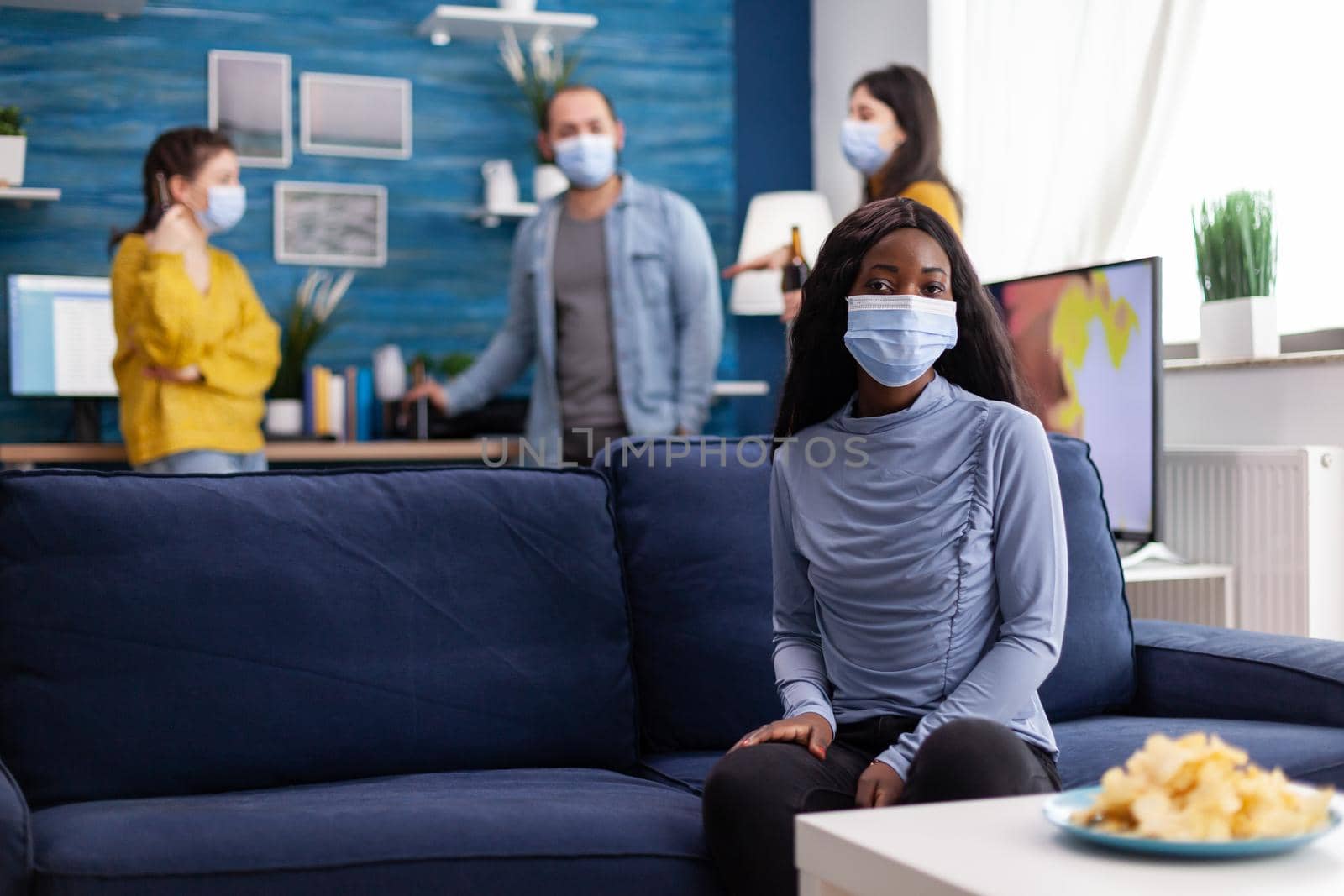 Cheerful african woman enjoying time with friends keeping social distancing wearing face mask to prevent spreading of covid19 as safety precaution following social distancing.