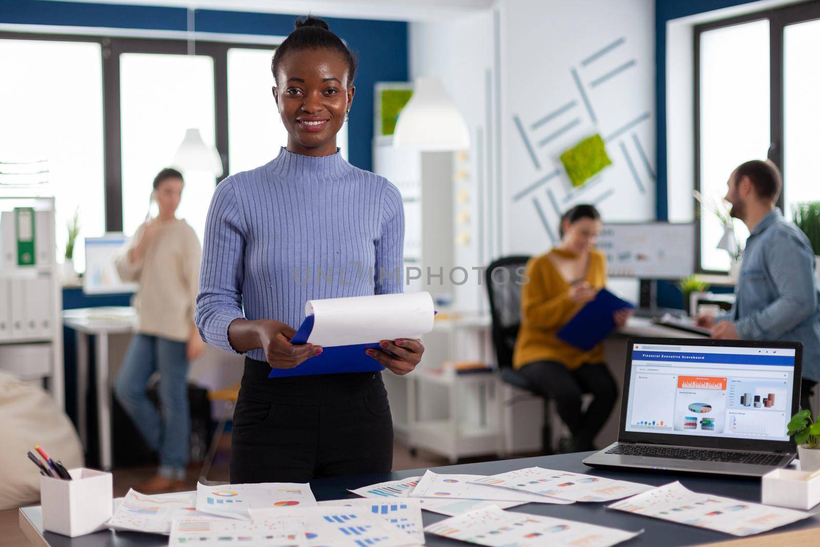 Smiling black woman entrepreneur holding clipboard with company strategy by DCStudio