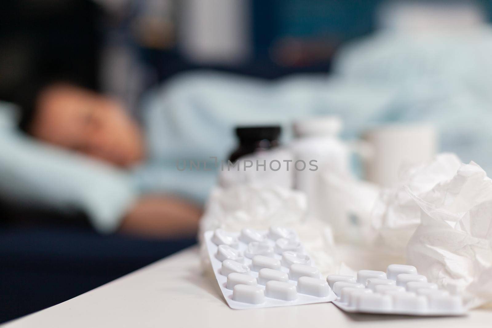 Close up of bottles and pills for sick woman with virus by DCStudio