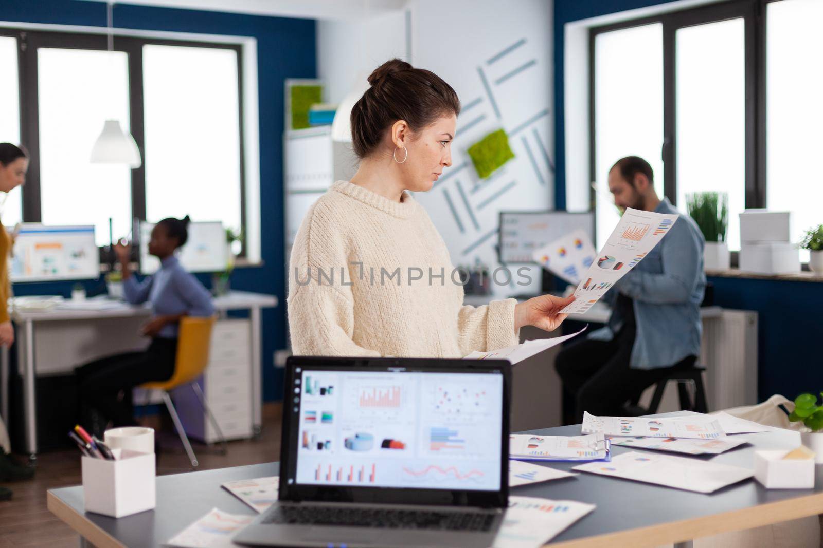 Corporate businesswoman reading statistics in start up company office. Successful corporate professional entrepreneur online internet statistics. Executive entrepreneur, manager leader standing working on projects with diverse colleagues.