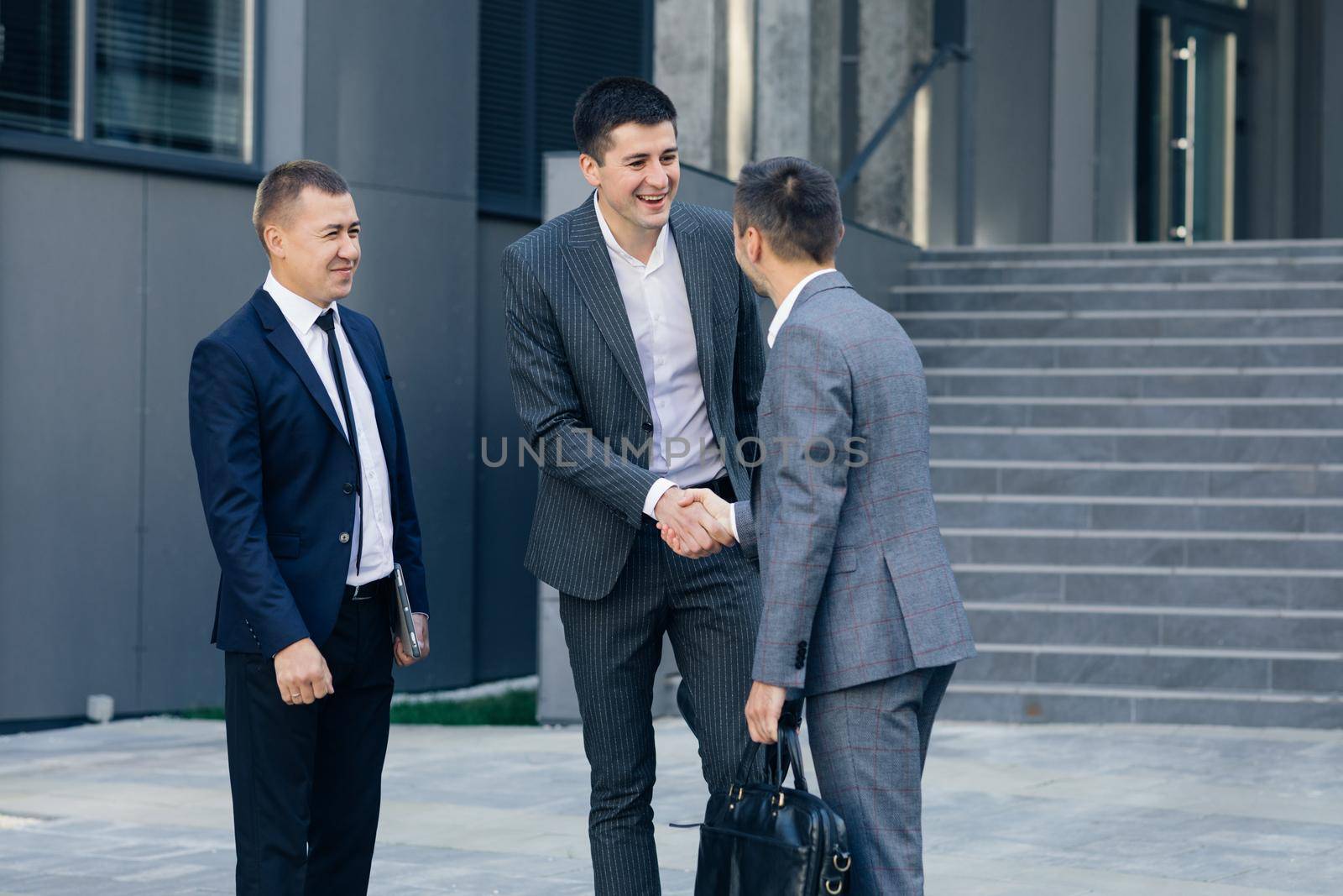 Group of Happy Men Corporate Workers Greeting Each Other Shaking Hands Starting Their Working Day in Contemporary Business District