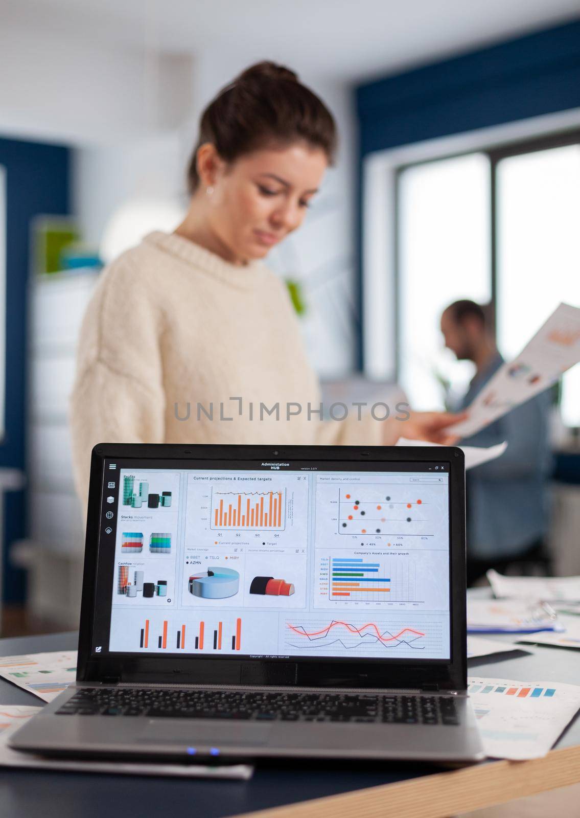 Laptop with financial charts on office of start up company. Executive entrepreneur, manager leader standing working on projects with diverse colleagues. Successful corporate professional entrepreneur online internet statistics