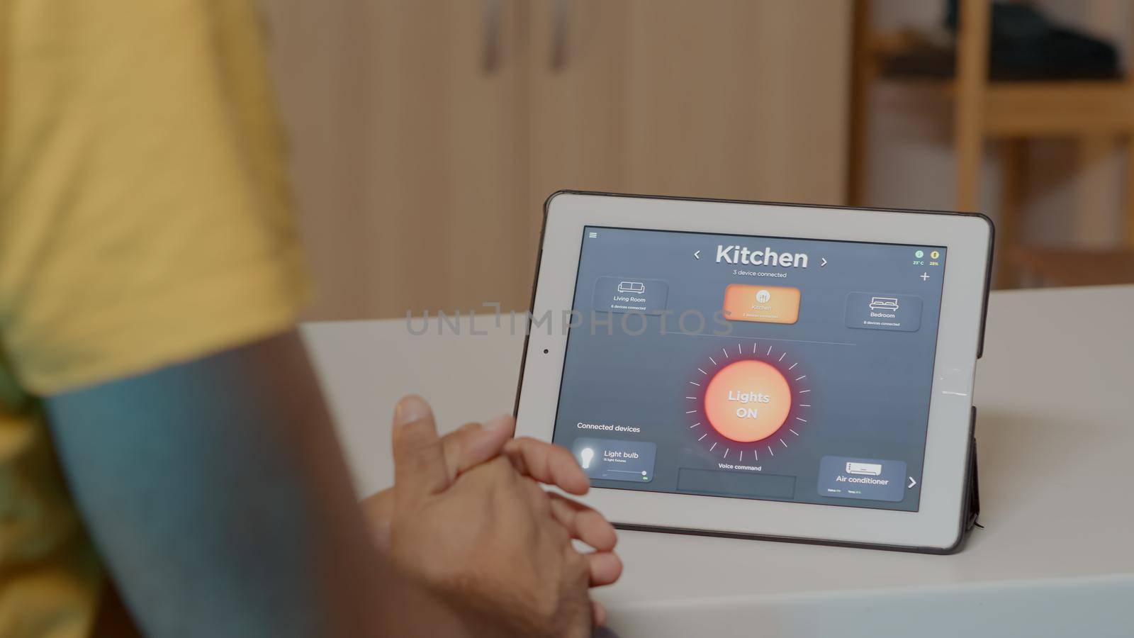 Man using voice activated smart wireless lighting app on tablet turning on the bulbs in house with modern software. Person controlling ambience light with future technology, voice activation command