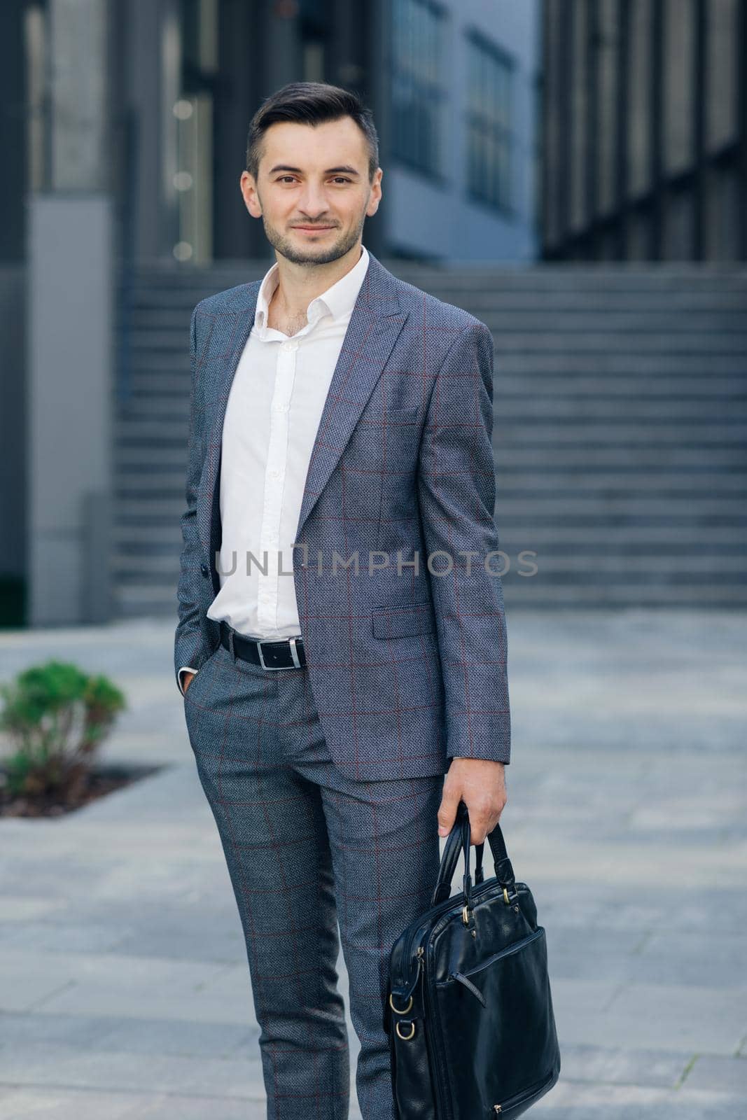 Portrait of a handsome businessman standing outdoors near office building. Businessman with suitcase by uflypro