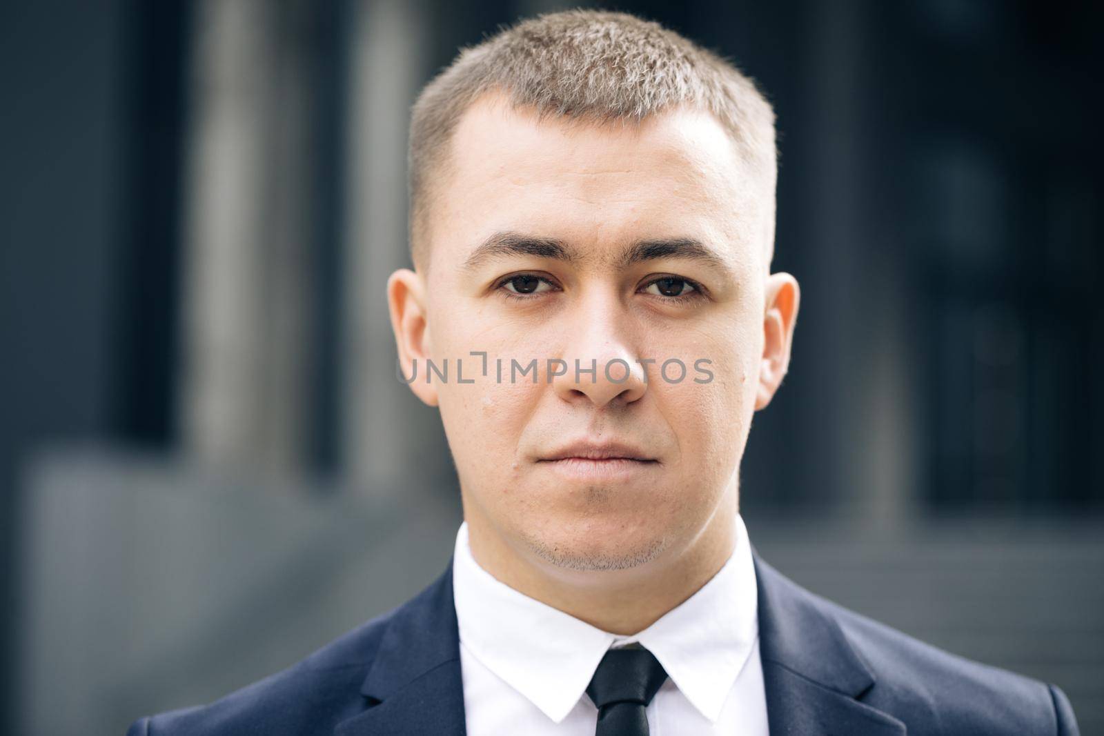 Portrait of handsome nice entrepreneur in formal suit standing outside work. Successful businessman. Corporate people. Office manager. Businessman standing look at camera near business center by uflypro