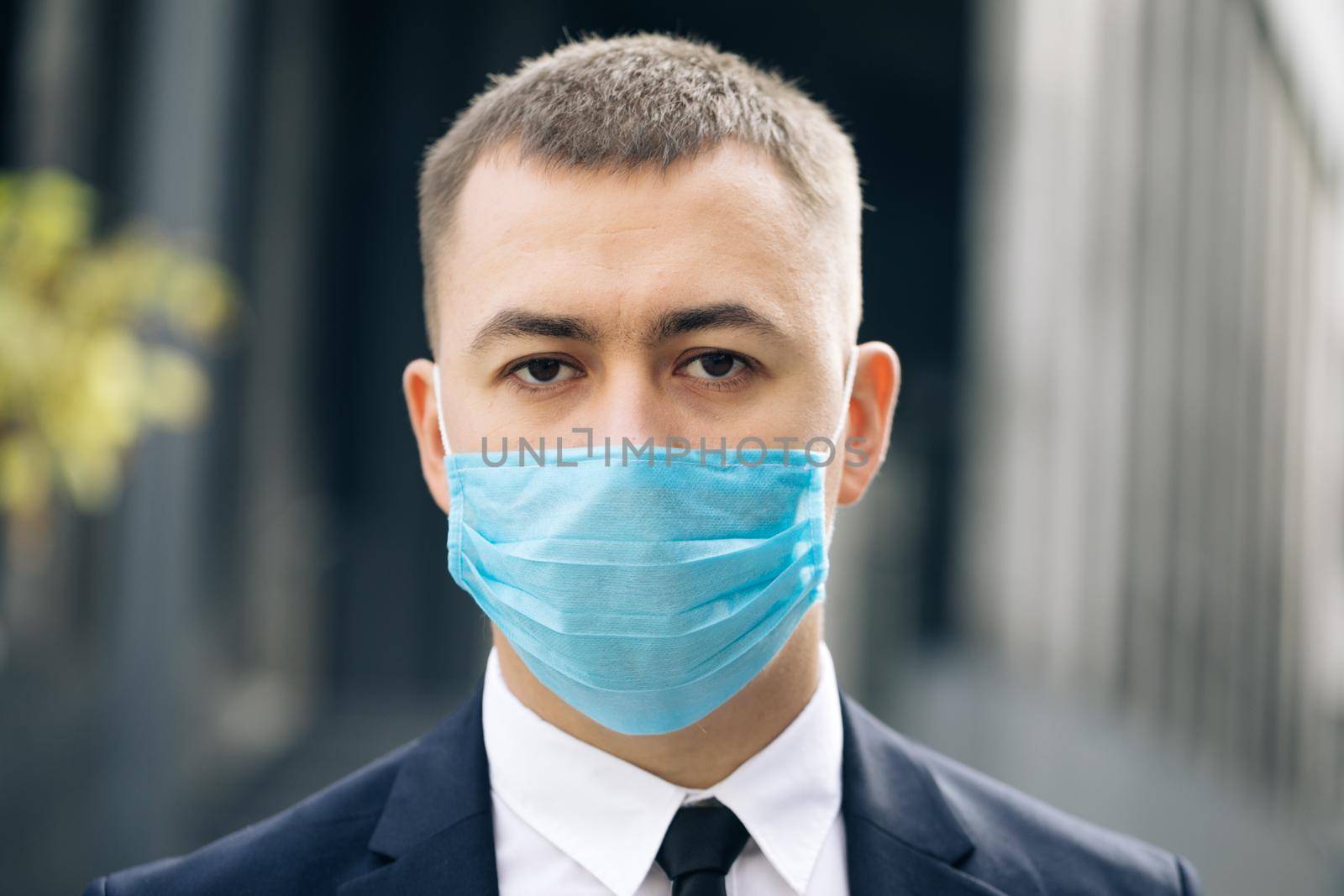 Portrait of a young businessman wearing protective mask on street. The concept health and safety, N1H1 coronavirus quarantine, virus protection. Pandemic Flu Corona Virus.