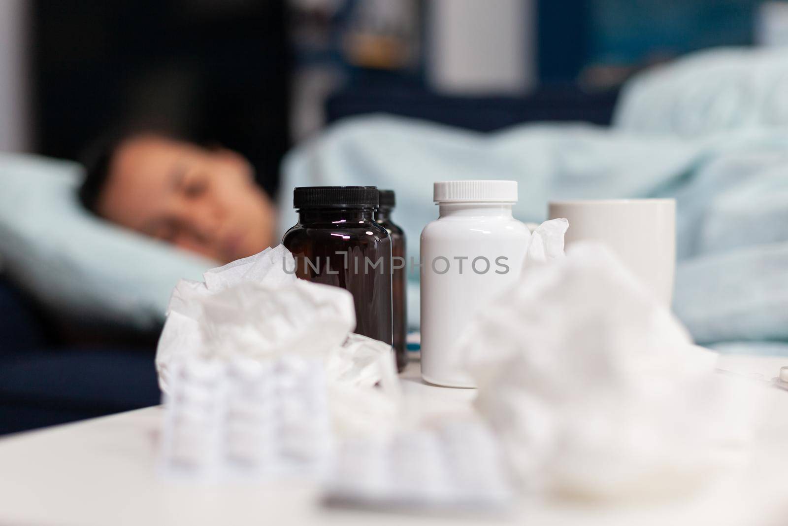 Close up of bottles and pills for sick woman with virus. Person taking medicine being unhealthy, having cold flu and fever symptoms. Adult on medication against infection and headache.