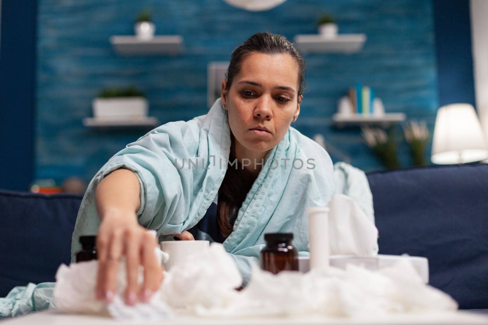 Sick woman taking medicine for seasonal virus wrapped in blanket holding pills. Caucasian young person treating disease with medical treatment for covid 19 symptoms temperature pain