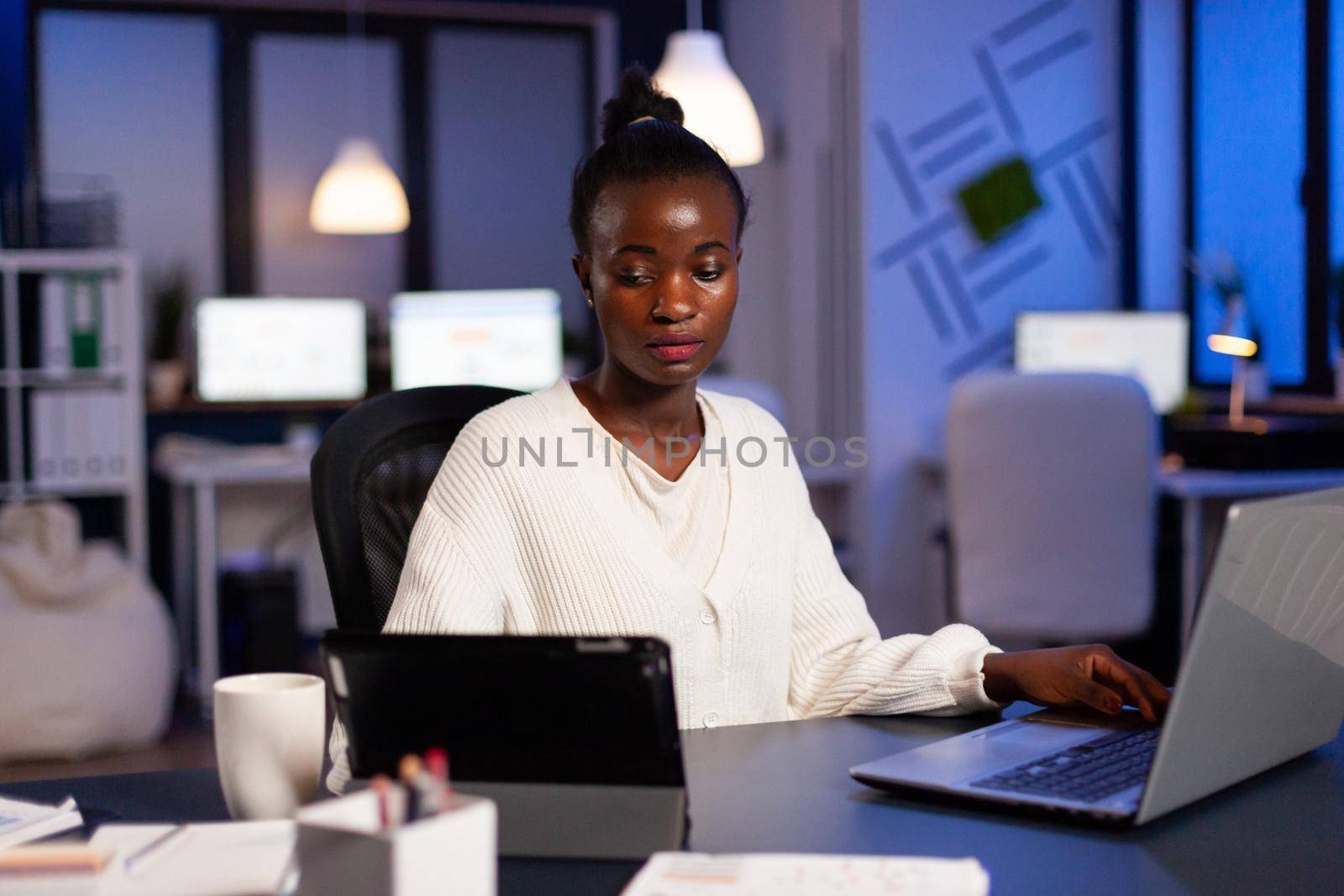 Overworked african businesswoman checking charts on tablet pc by DCStudio