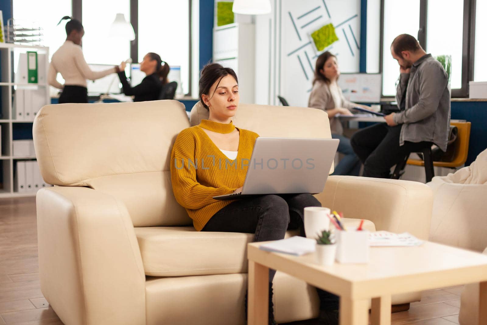 Succesfull business woman working on laptop on start up project sitting on cozy couch by DCStudio