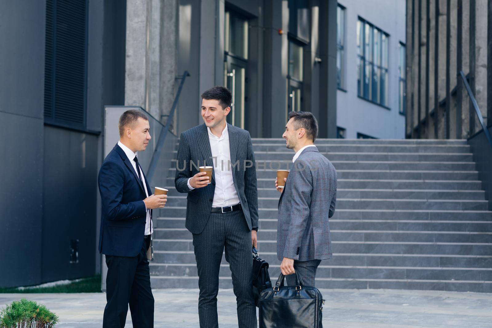 Group of entrepreneurs men in formal clothing are talking discussing business with drinks. People and communication concept.