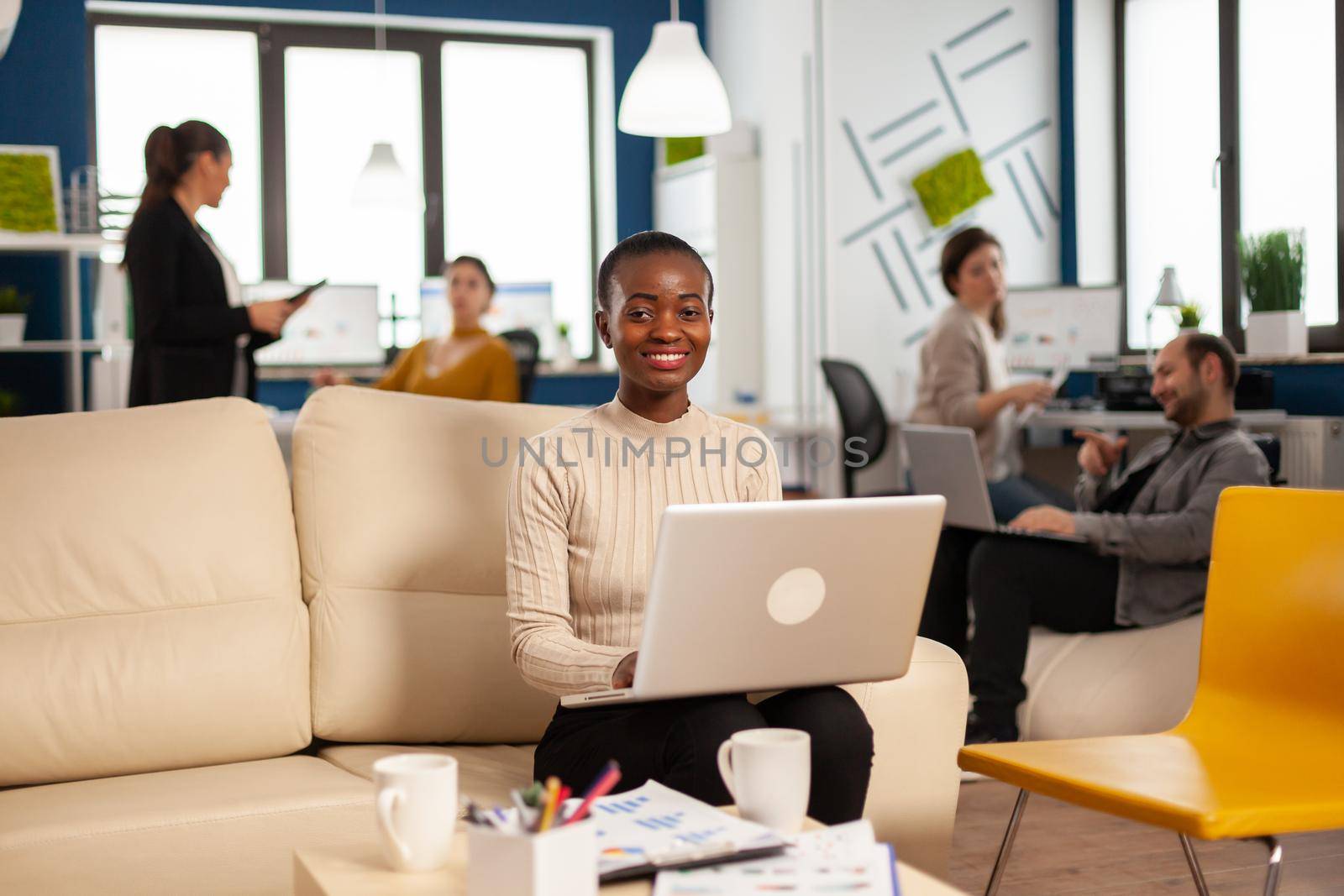 African woman manager sitting on couch in front of camera smiling by DCStudio