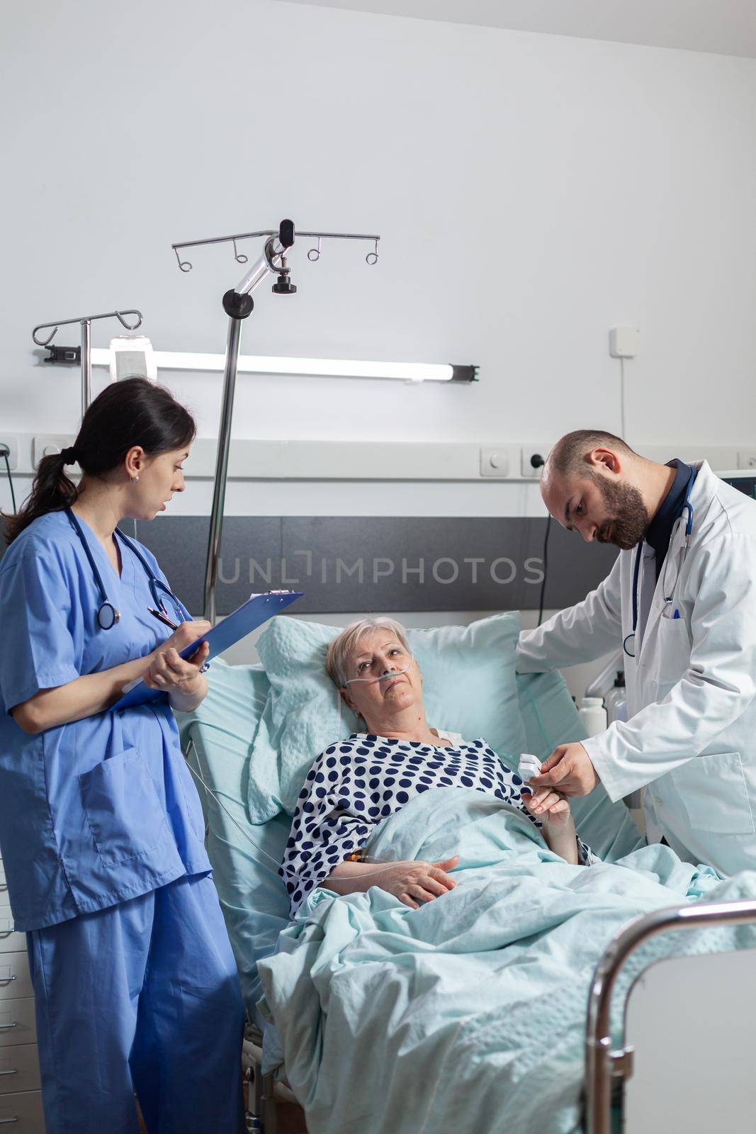 Nurse is taking notes on clipboard during consultation of senior woman by DCStudio
