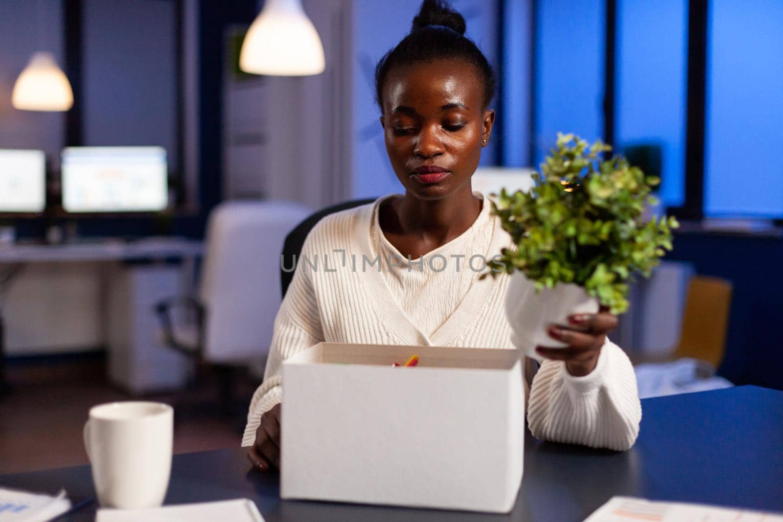 Depressed african woman after being dismissed from work late at night. Unemployed packing things late at night. woman leaving workplace office in midnight.
