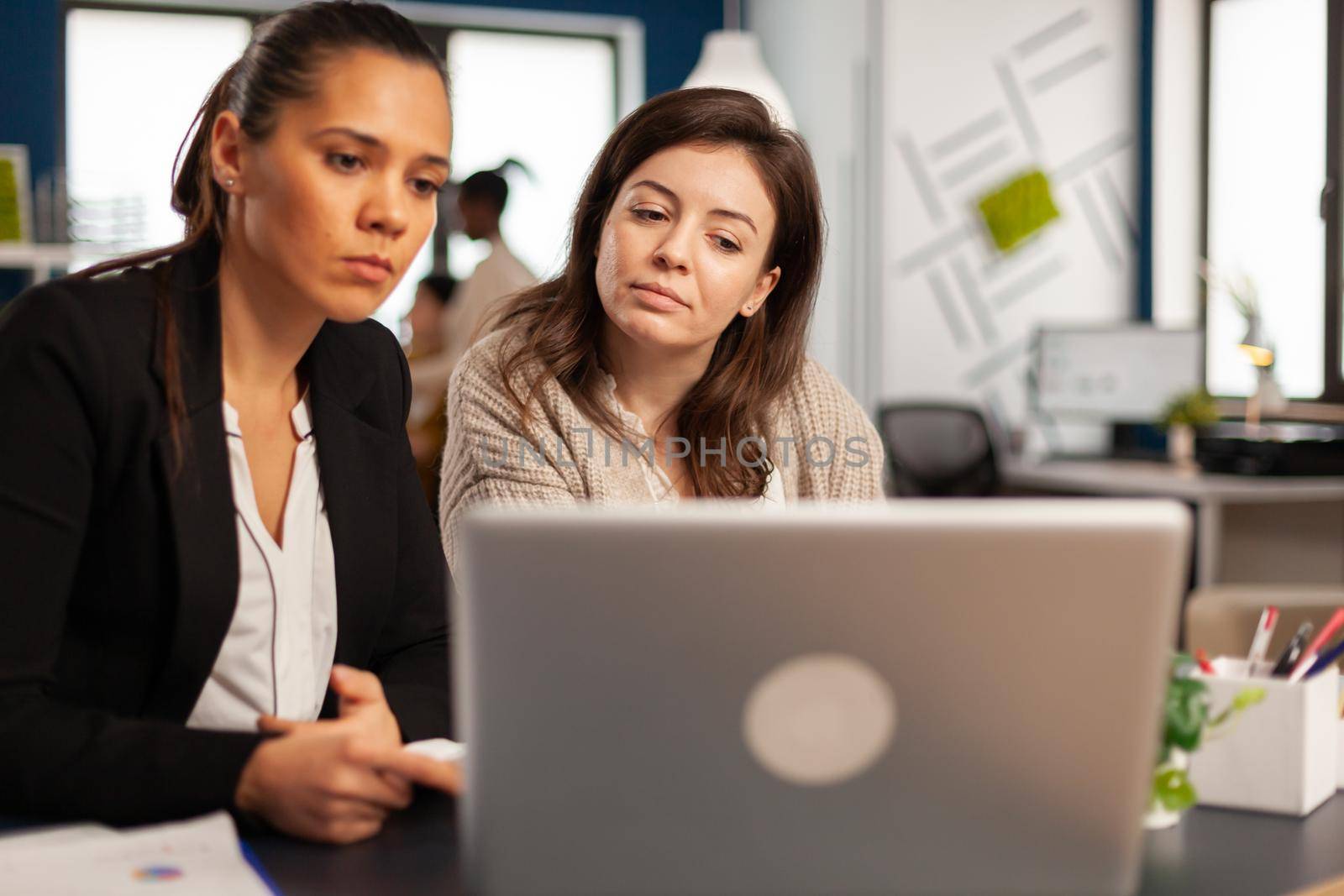 Close up of diverse businesswomen checking graphs from laptop by DCStudio