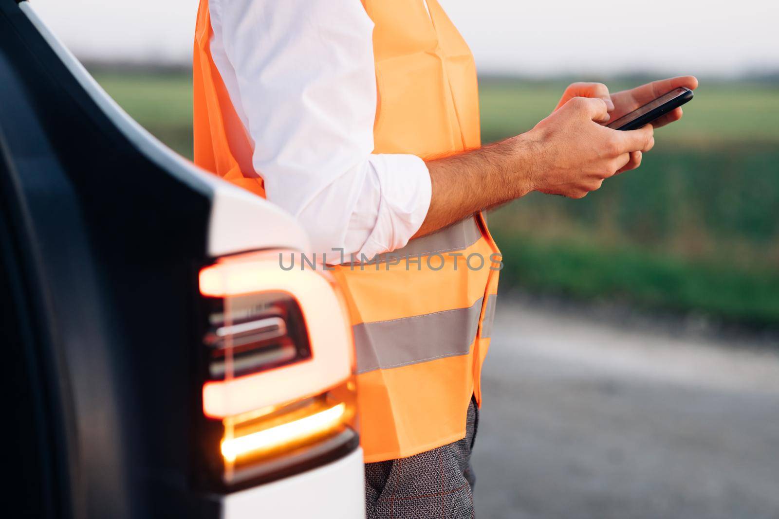 The man uses the phone after the electric car has broken down. Car Blinker Light or Emergency Light. The electric car had an accident. Car service by uflypro