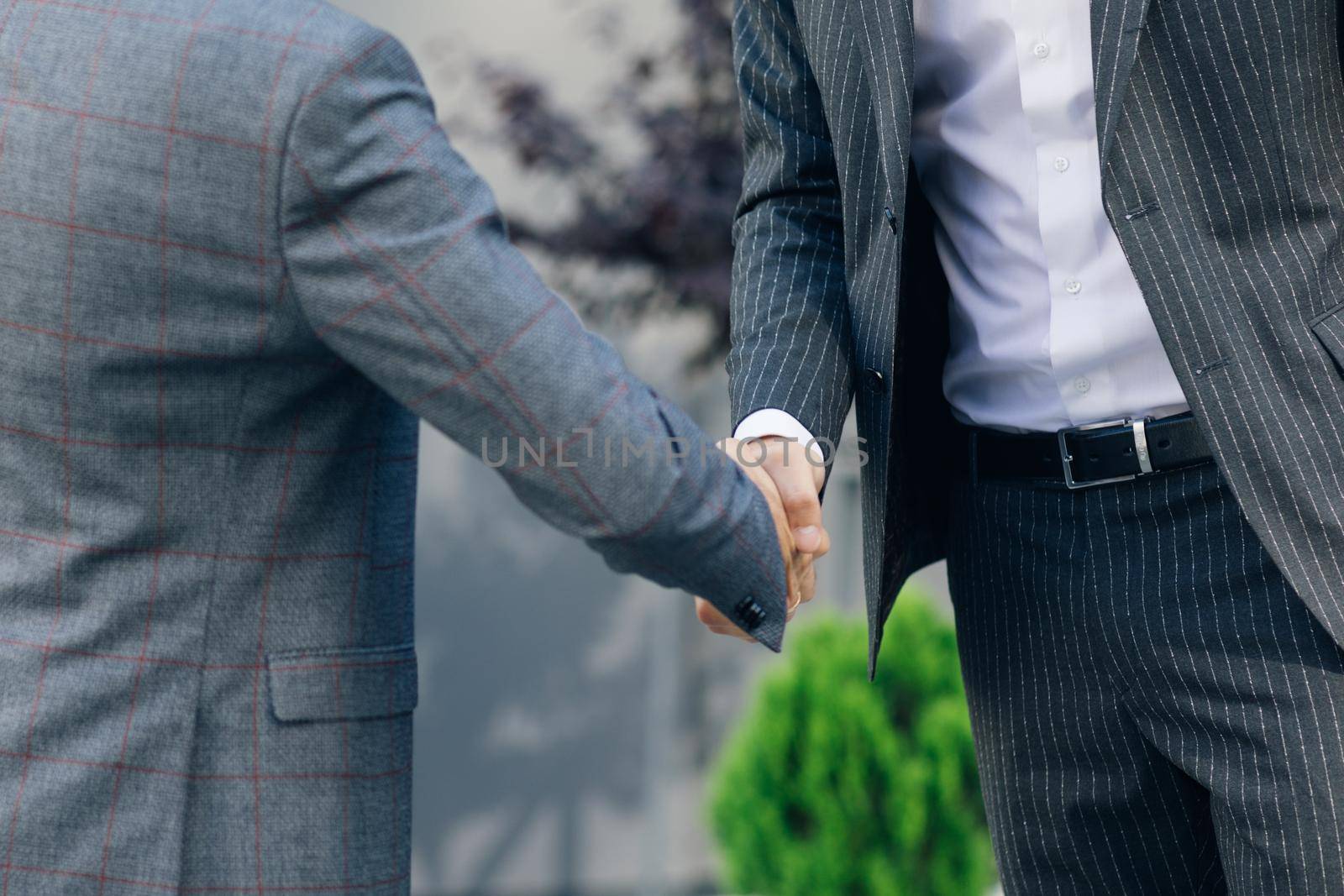 Hands of Top managers in Business Suits, shake hands with each other at Business center background. Agree to a deal or say hello. Unrecognizable person