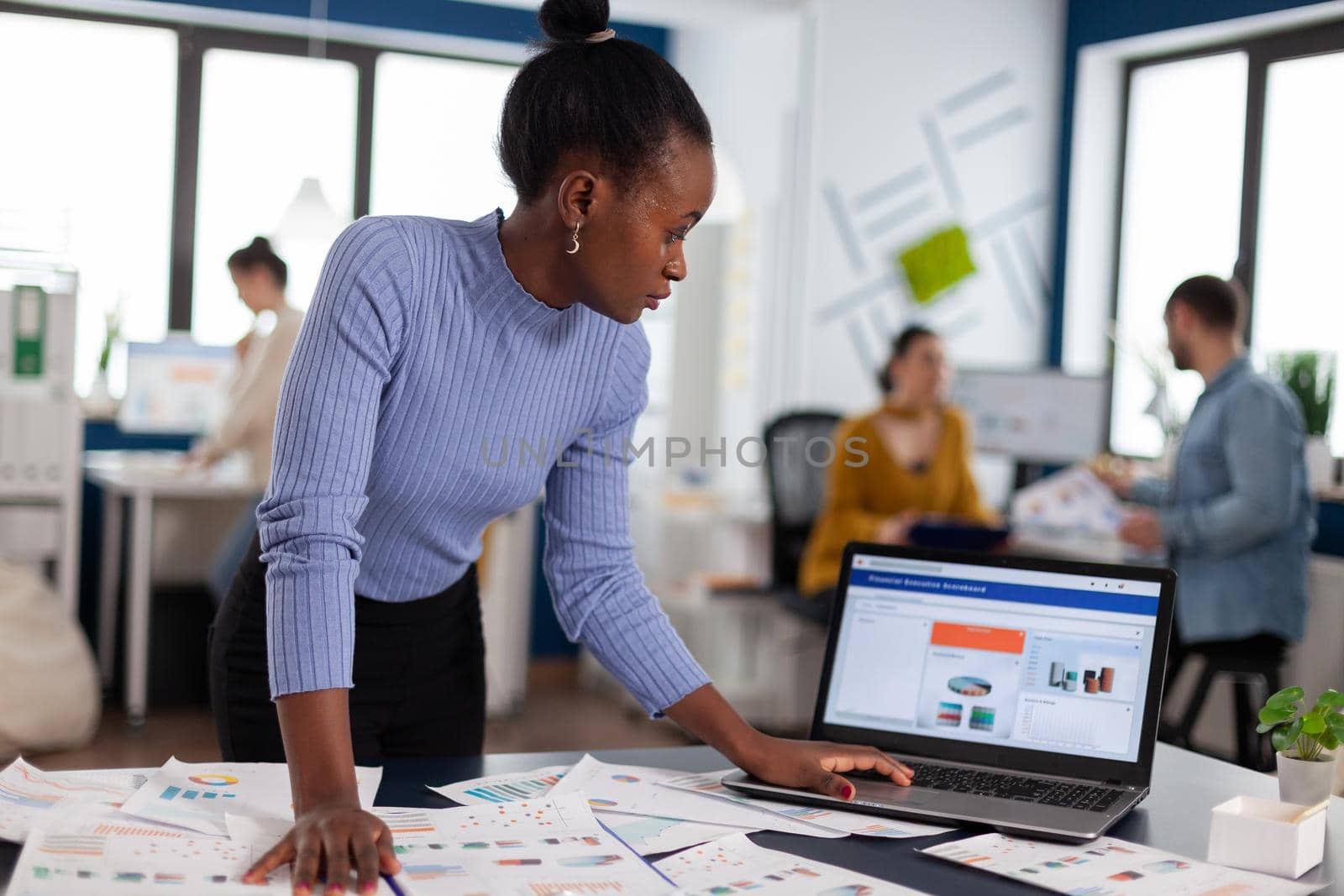 African woman scorlling on laptop looking at charts by DCStudio