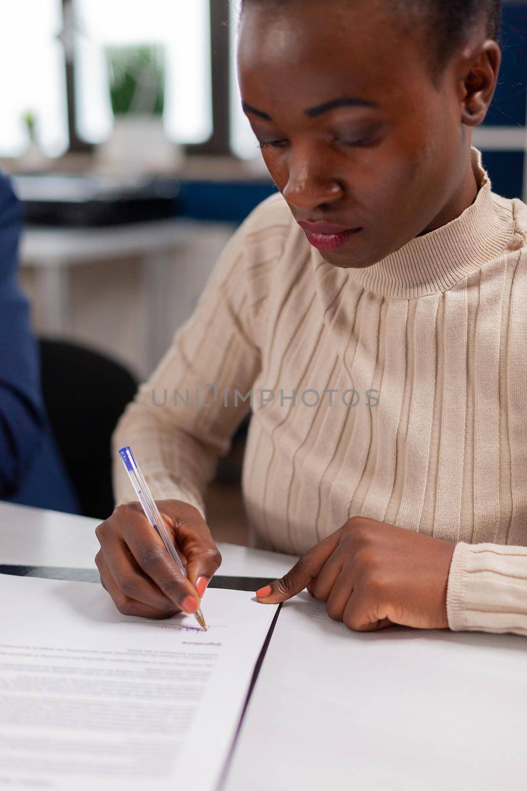 African businesswoman reading signing documents its while business partners sharing paperwork. Executive director meeting shareholders in start up office, making satisfactorily agreement.