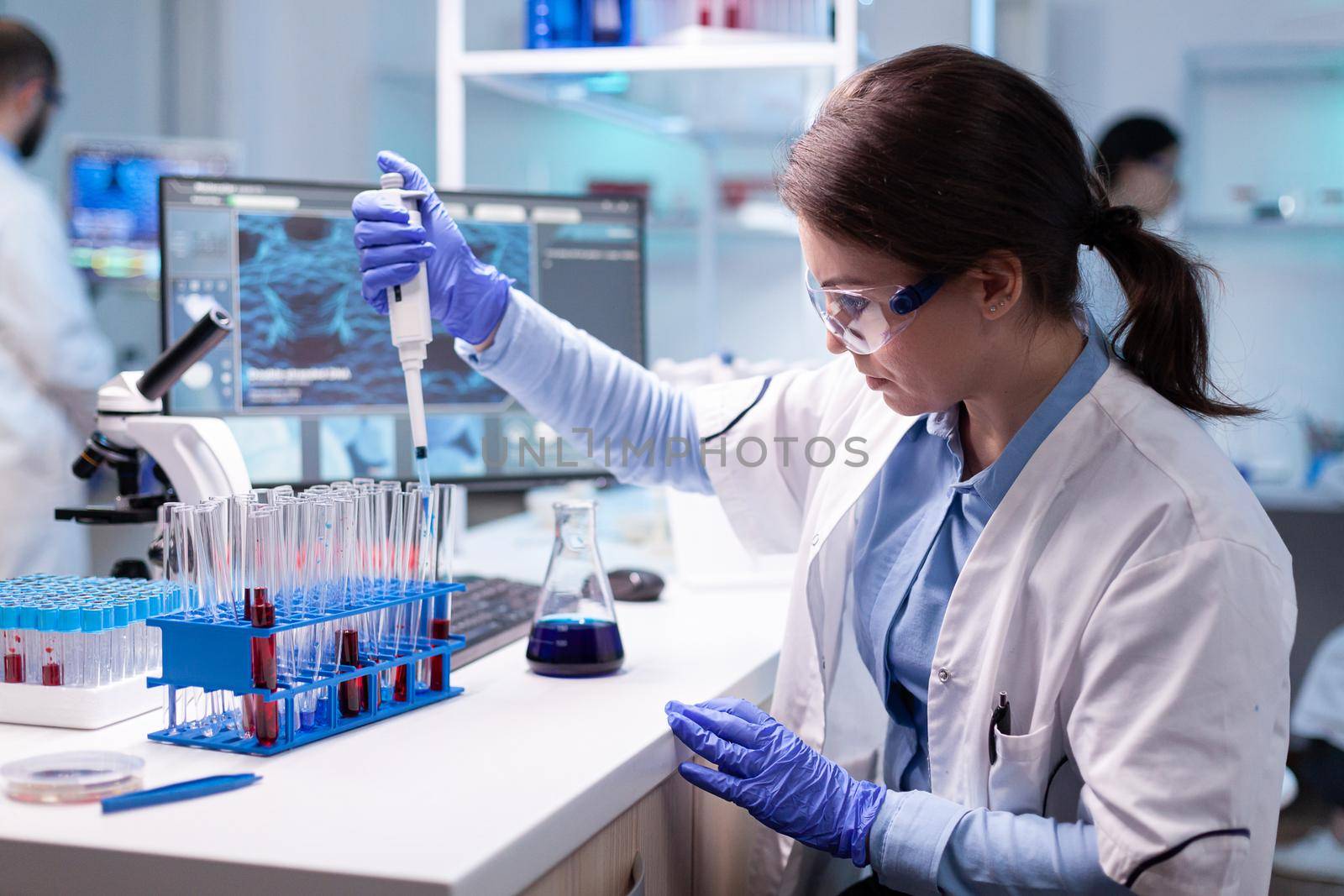 Concentrated professional woman scientist in laboratory working with a micropipette and a dropper. Biology doctor discovery scientifc experiment with technology equipment industry