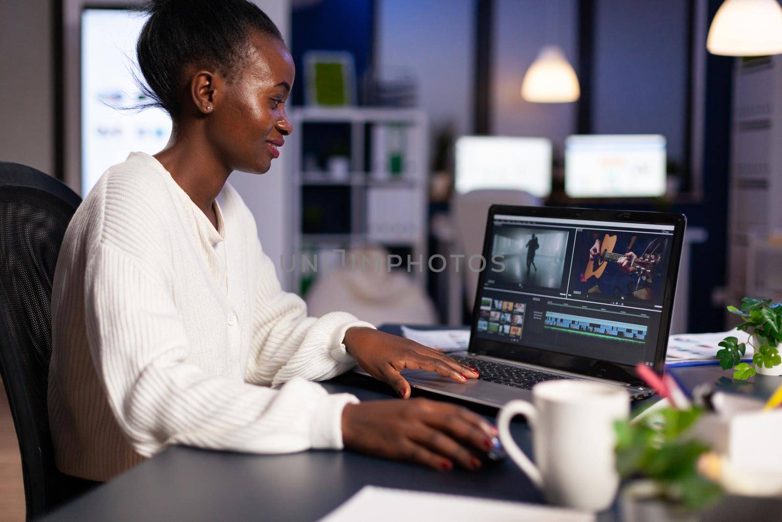 Black delighted videographer editing movie on professional laptop by DCStudio