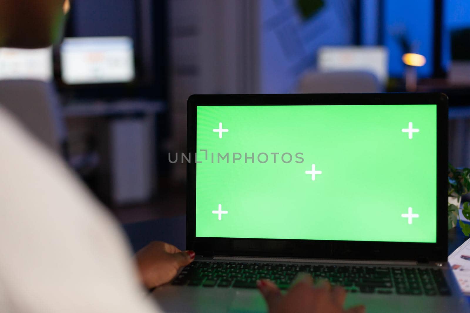 Back view of black business woman using laptop with green screen by DCStudio