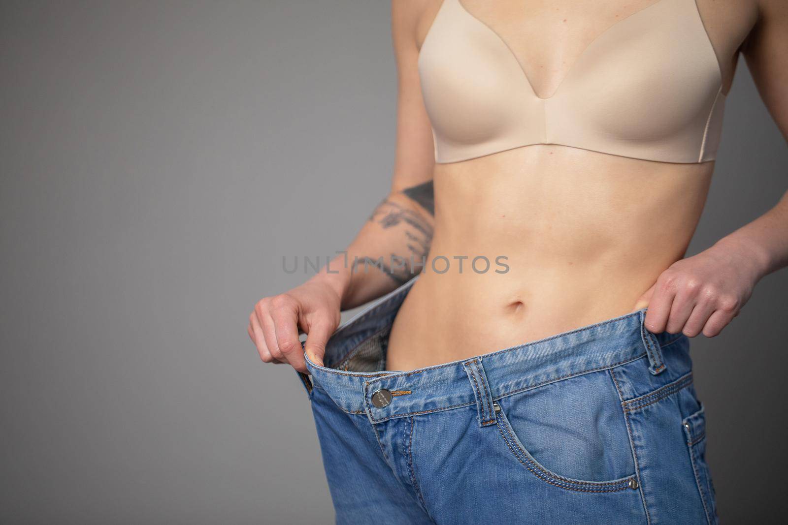 Woman Shows her Weight Loss and Wearing Her Old Jeans. Slim Girl in Big Jeans Showing How She Was Losing Weight When She Started Eating Healthy Food by uflypro