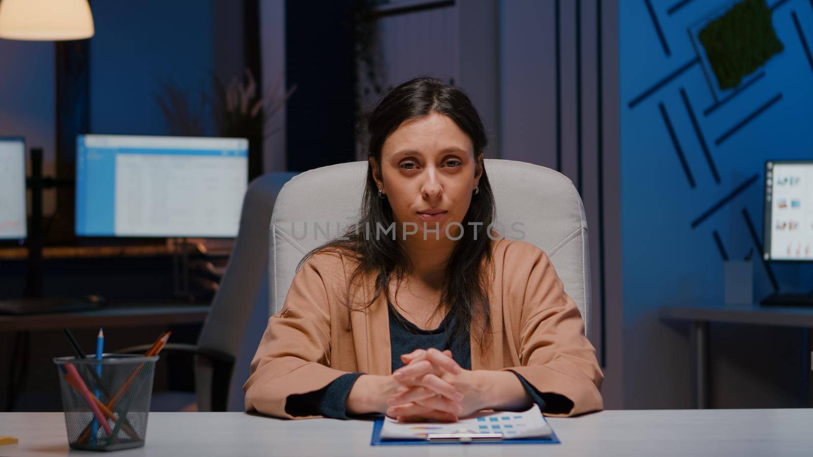 Pov of exhausted businesswoman talking with remote business team discussing marketing project deadline during online videocall conference meeting. Tired entrepreneur working in startup company office