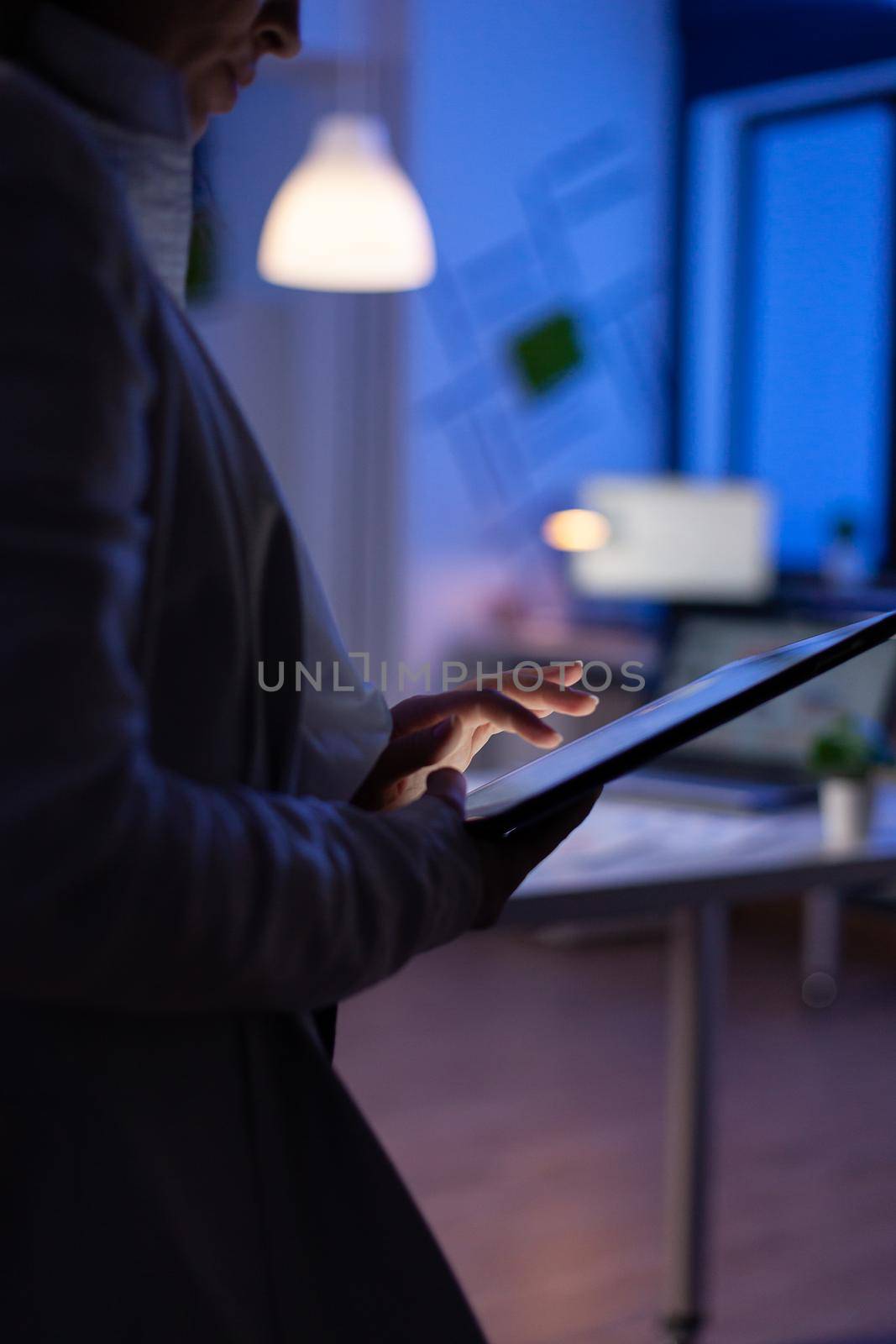 Close-up photo of manager woman hands typing on tablet checking financial graphs standing in start-up office . Businesswoman using social network working on marketing project late at night