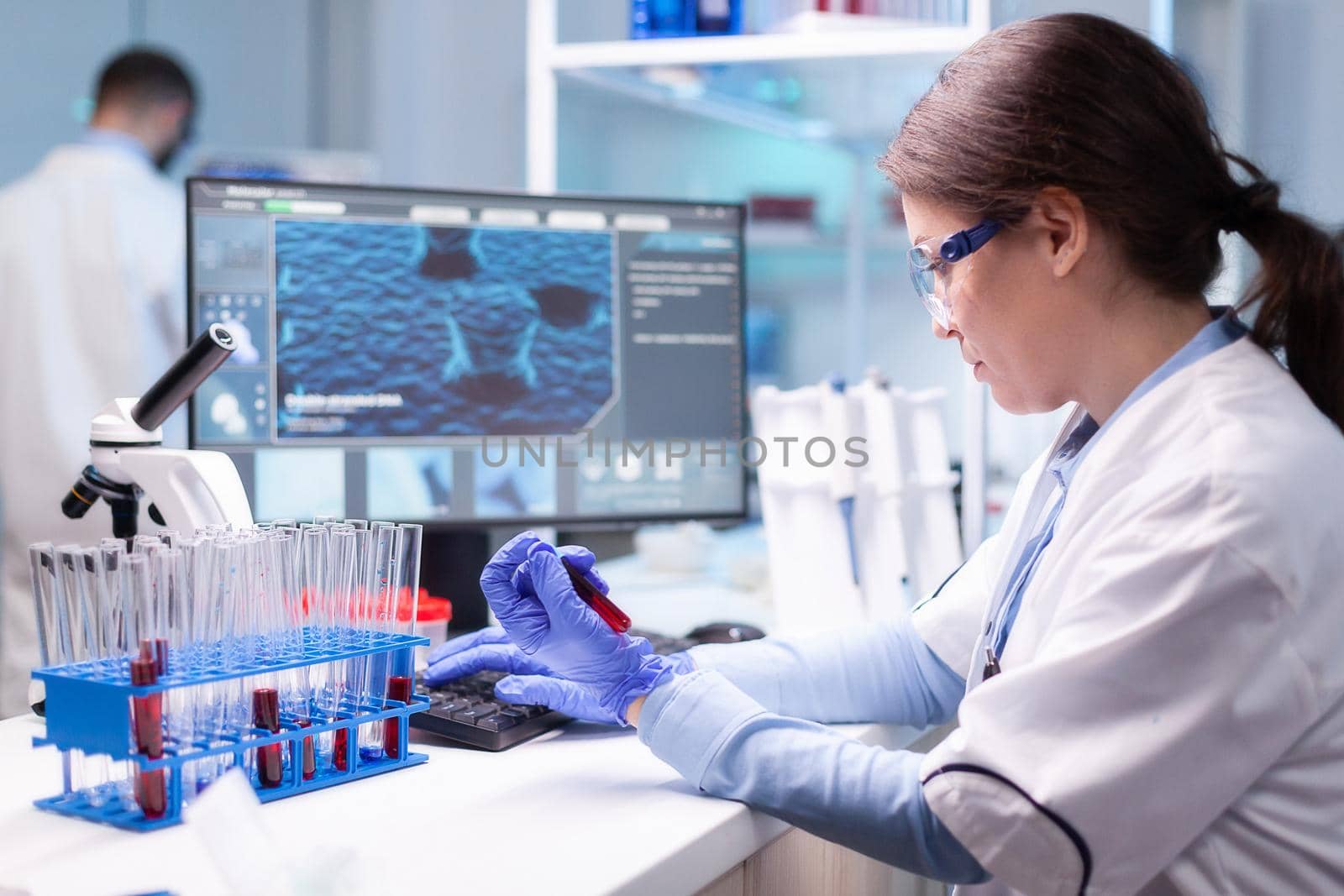 Professional scientist looking at analysis of blood tube for medical experiment by DCStudio