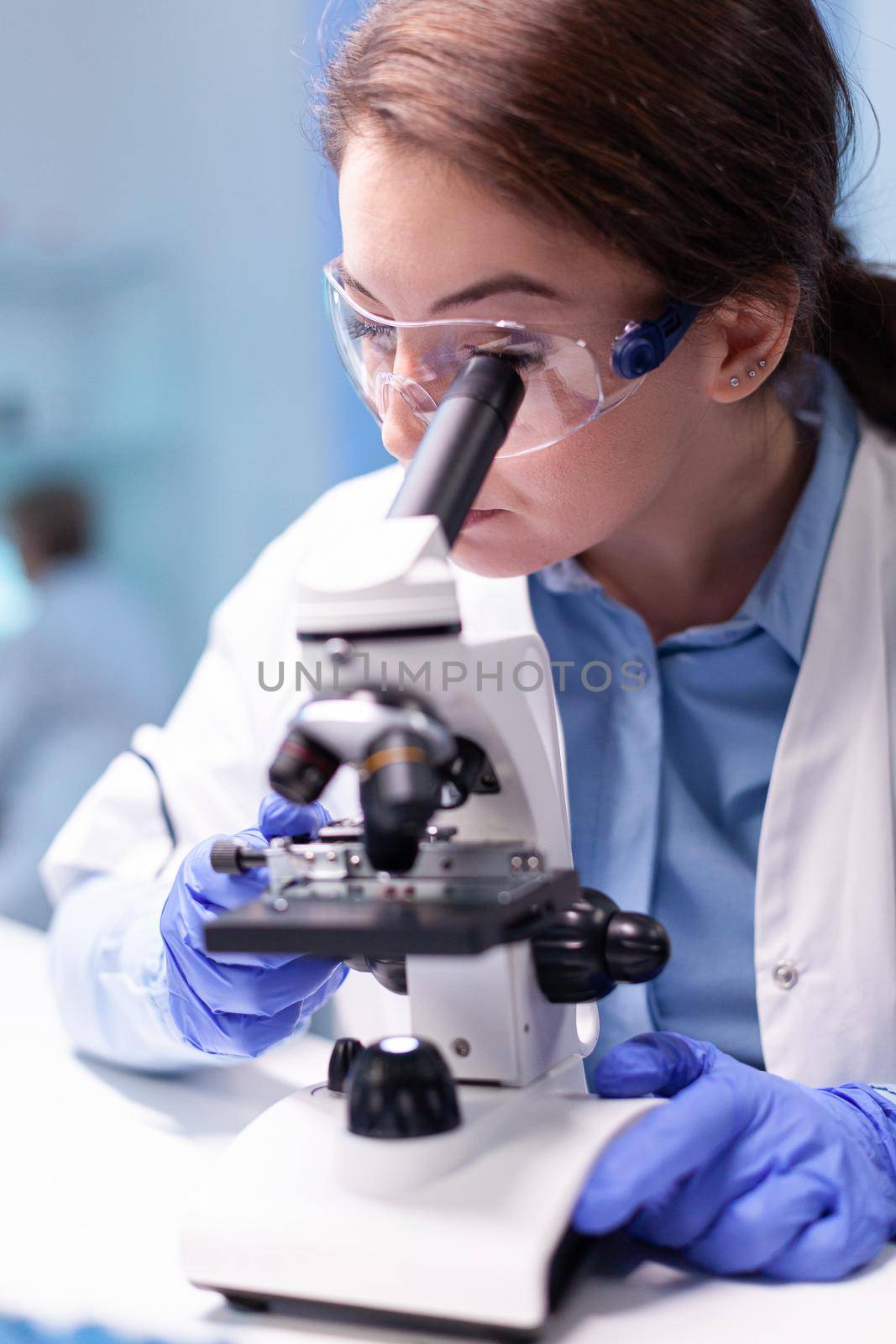Doctor chemist researcher in white coat working with microscope in clinic discover by DCStudio