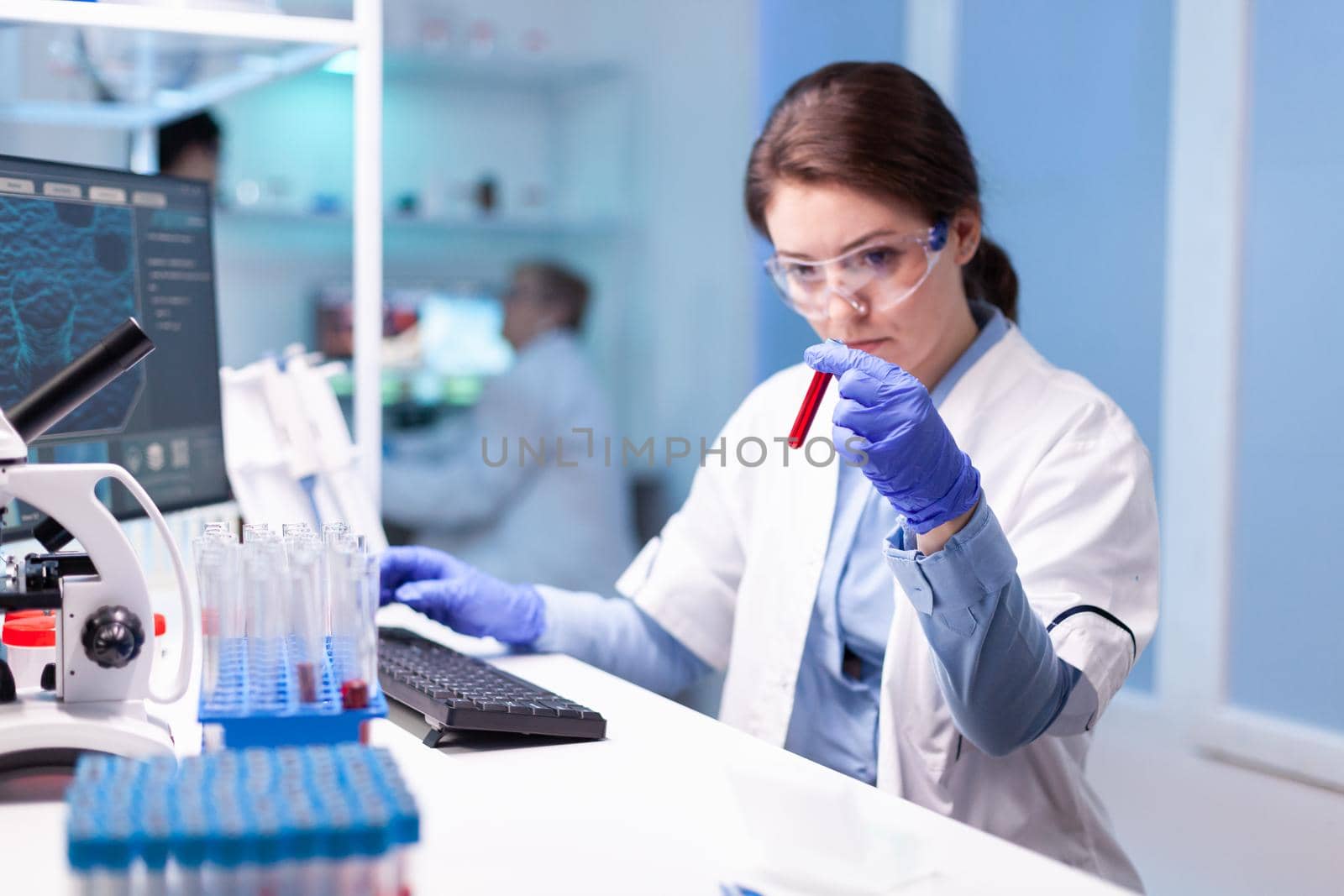 Biotechnologist woman scientist researching with a blood tube in pharma lab. Modern laboratory for scientific research with professional equipment for virus study and healtcare