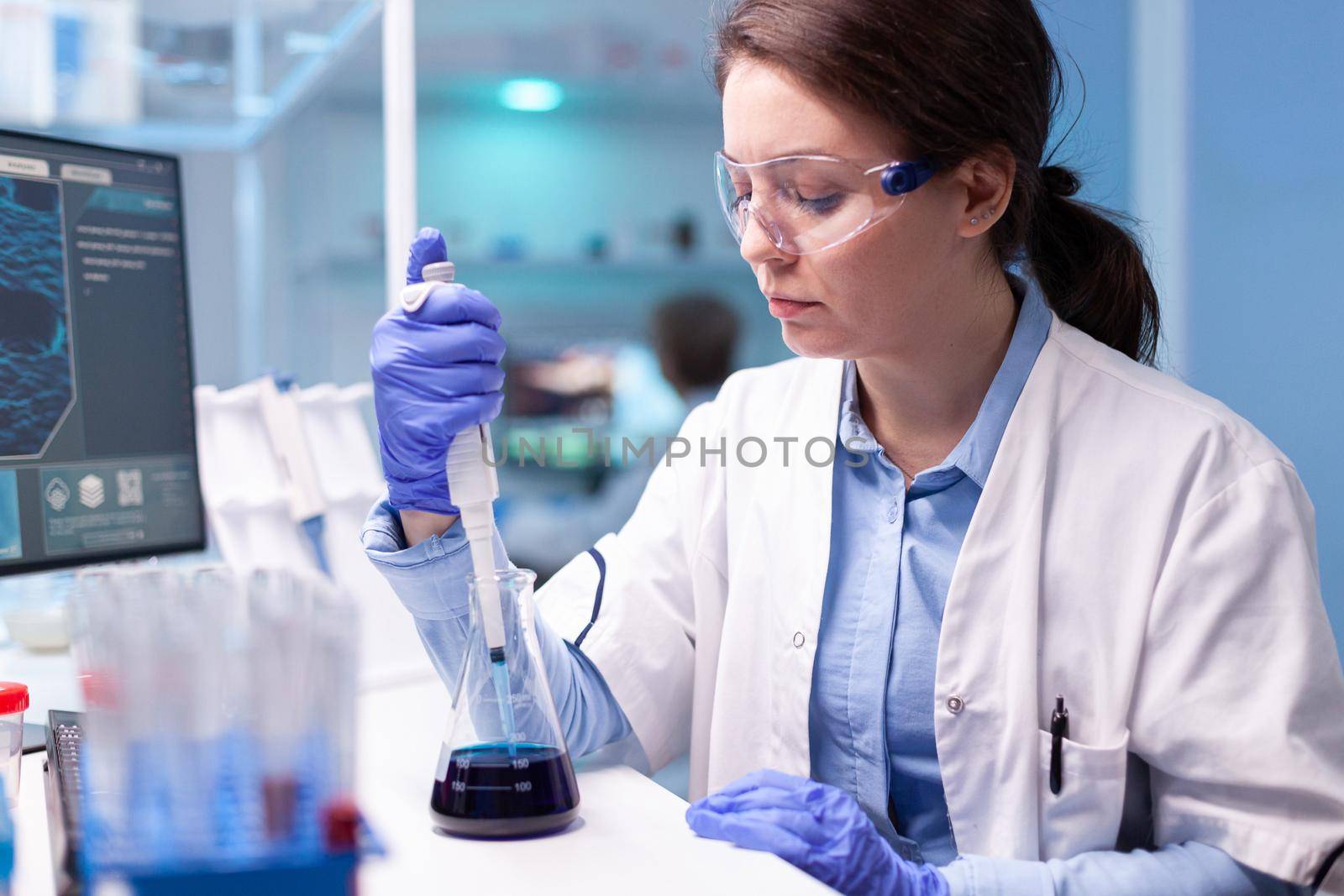 Scientist doctor in white coat discovering genetic infection and analysing micropipette. Woman research a new experiment in modern lab, analyzing pharmaceutical work with modern equipment.