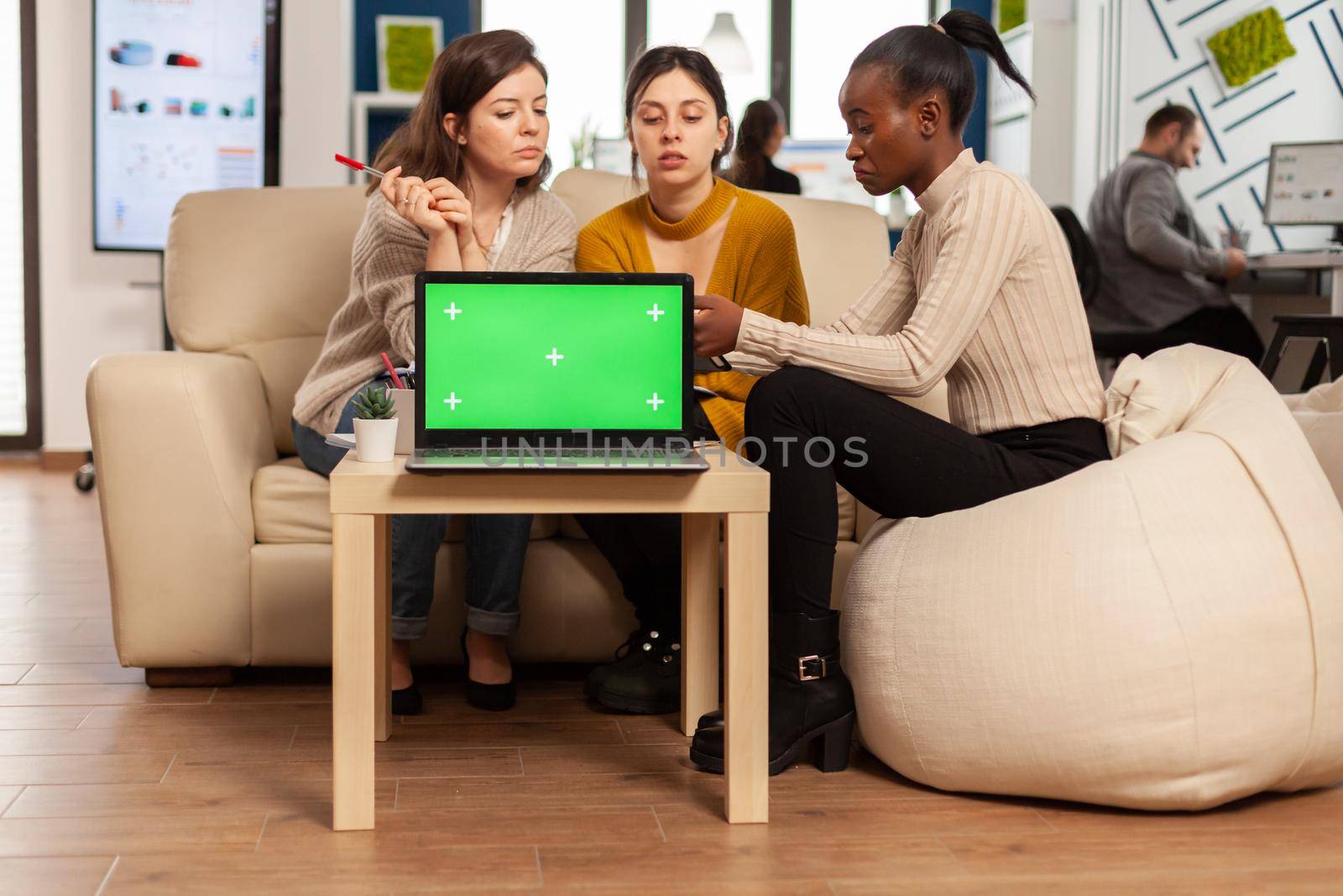 Laptop with green screen on table in start up company by DCStudio