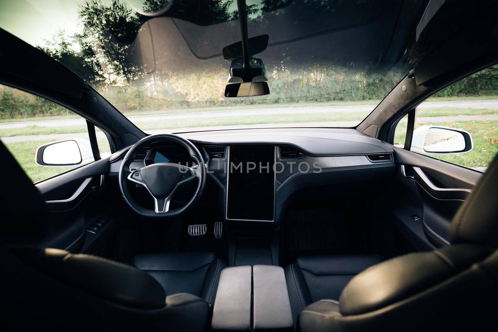 Electric car interior details of door handle with windows controls and adjustments. Inside car interior with front seats, driver and passenger textile windows door panels console by uflypro
