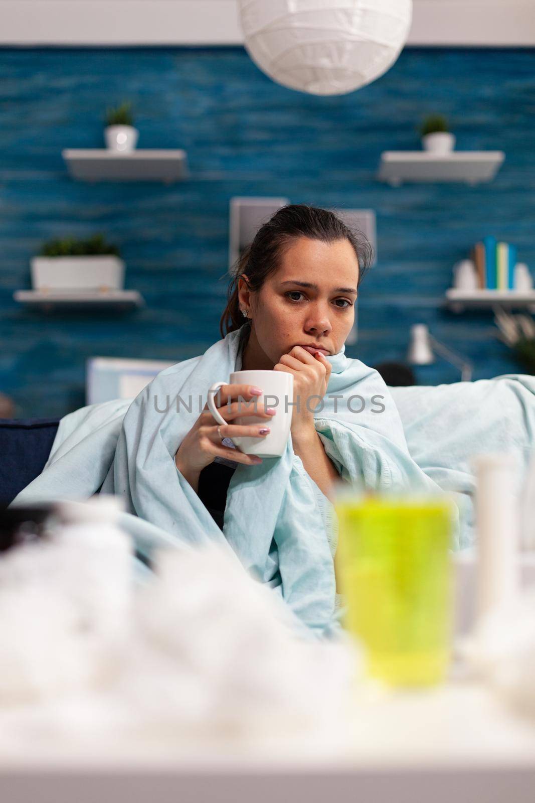 Woman with flu sitting at home drinking hot tea by DCStudio