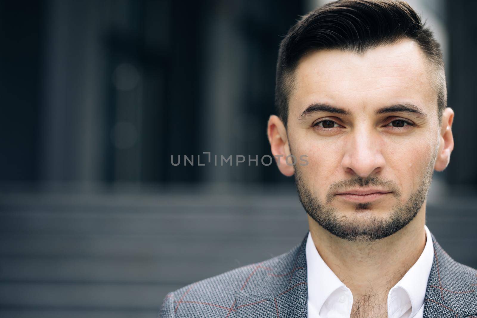 Portrait of handsome nice entrepreneur in formal suit standing outside work. Successful businessman. Corporate people. Office manager. Businessman standing look at camera near business center. by uflypro