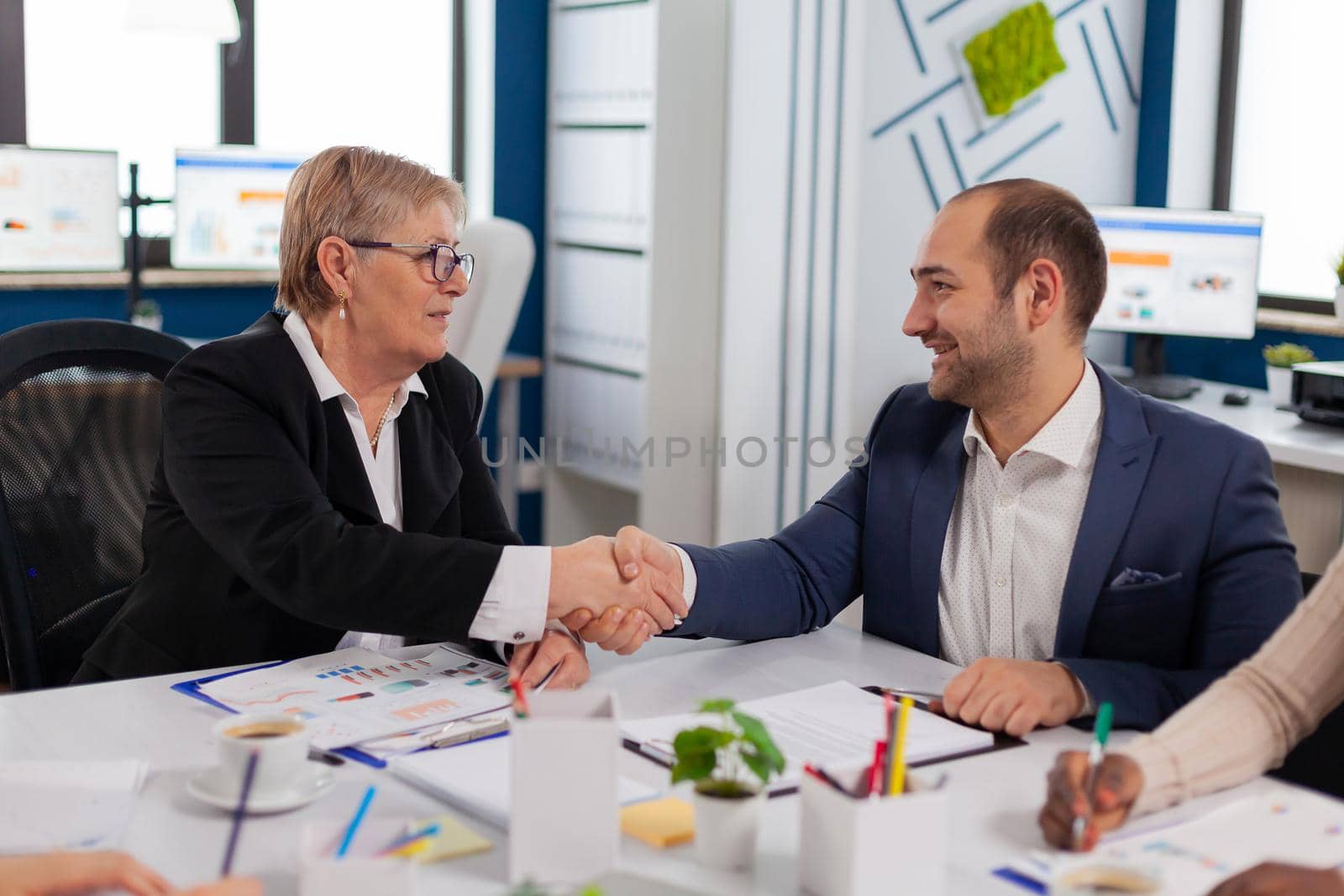 Consultant greeting international client with handshake after partnership by DCStudio