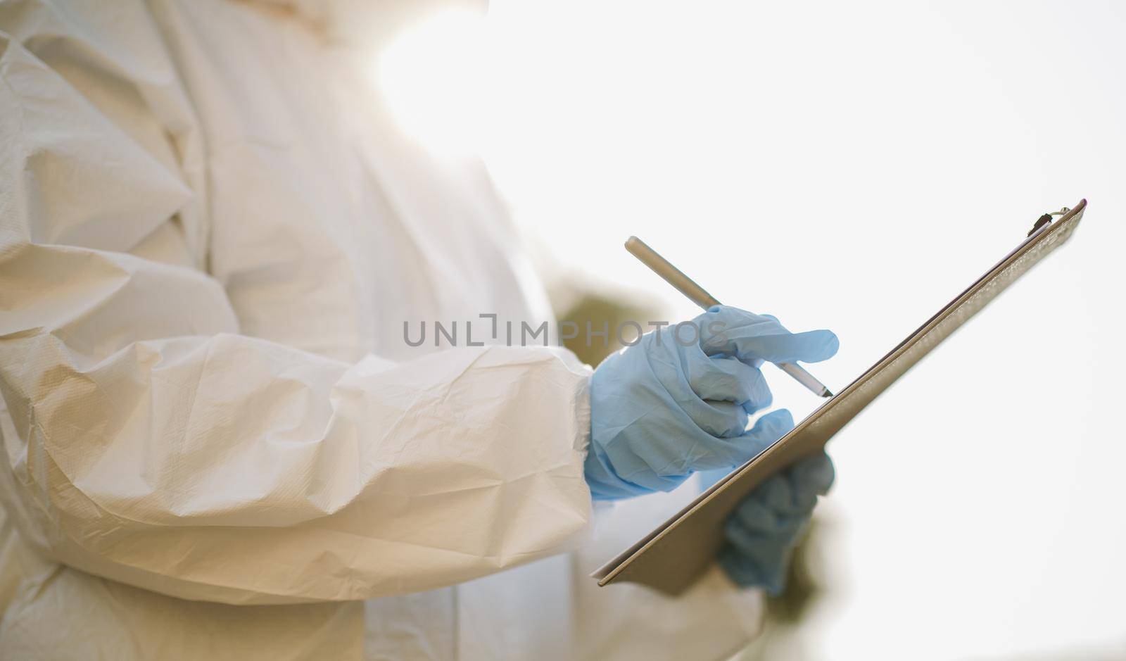 Doctor woman Virologist is writing a medical recipe or doctor prescription or diagnostic results concept. The girl's hand in a white glove holds a pen on a blank sheet of paper.