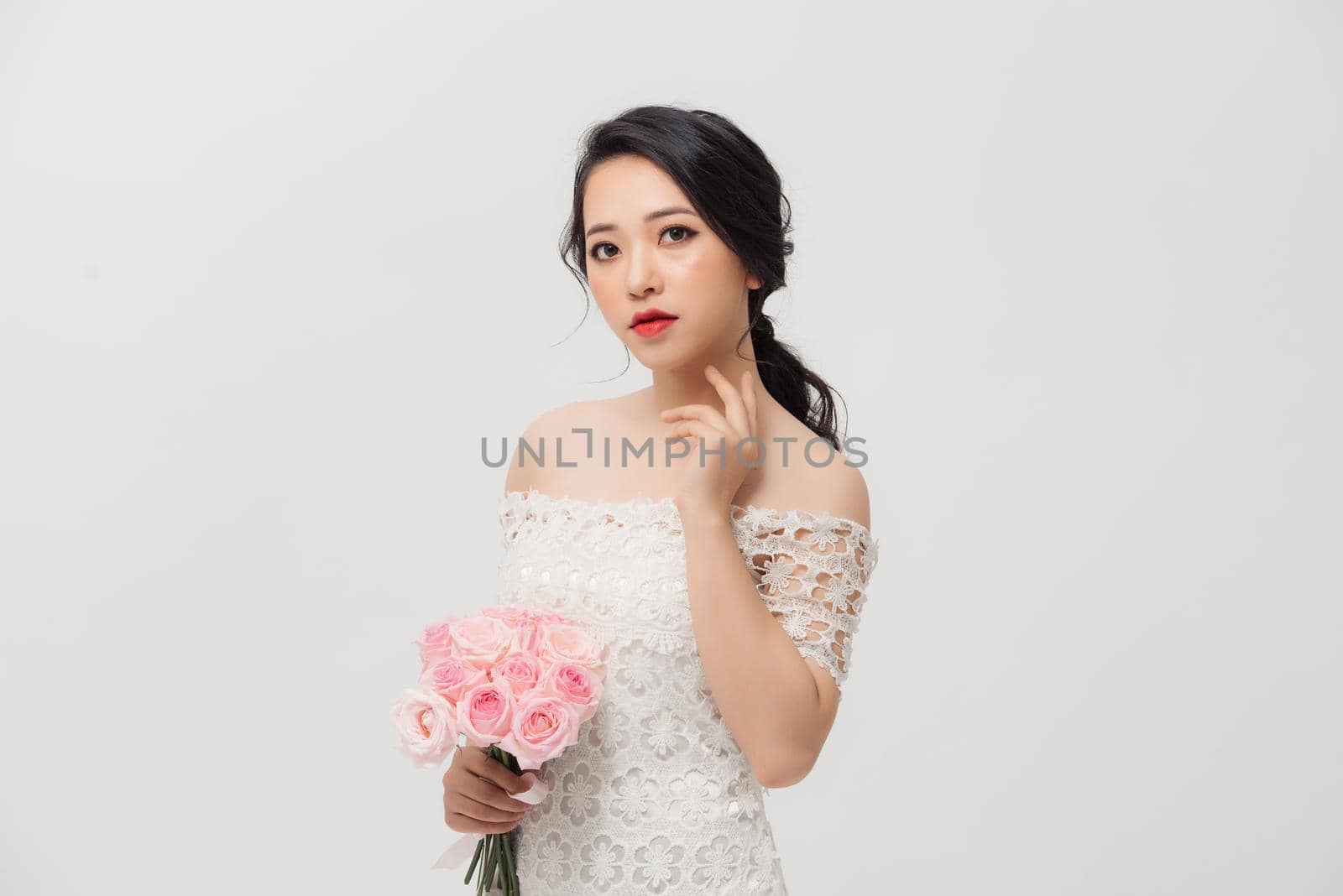 Fashion portrait of elegant woman with rose flower bouquet over white background.