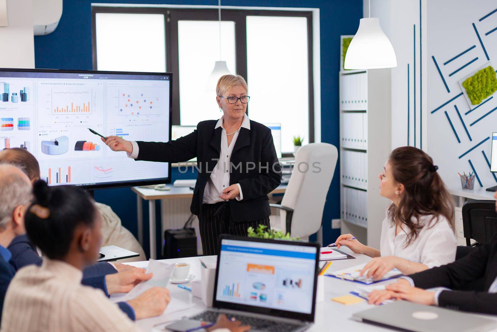Senior startup businesswoman holding presentatin in conference room by DCStudio