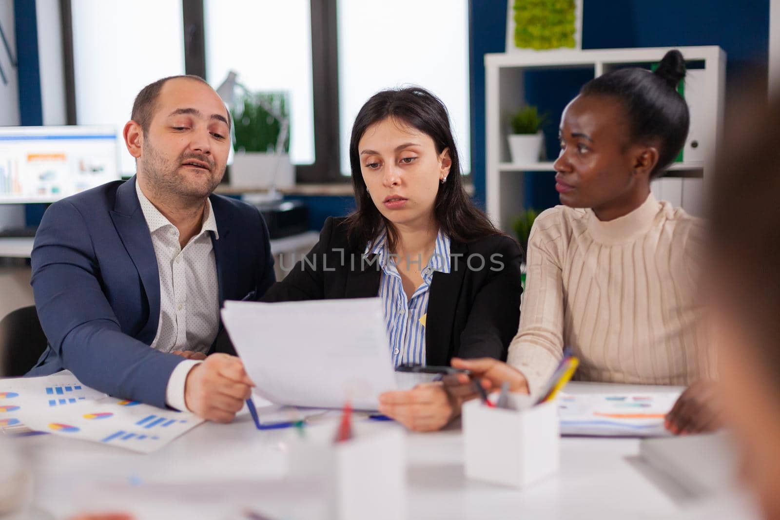 Successful businessman and coworkers discussing in conference room about documents planning. Executive explaining company's vision to employees sitting at brainstorming