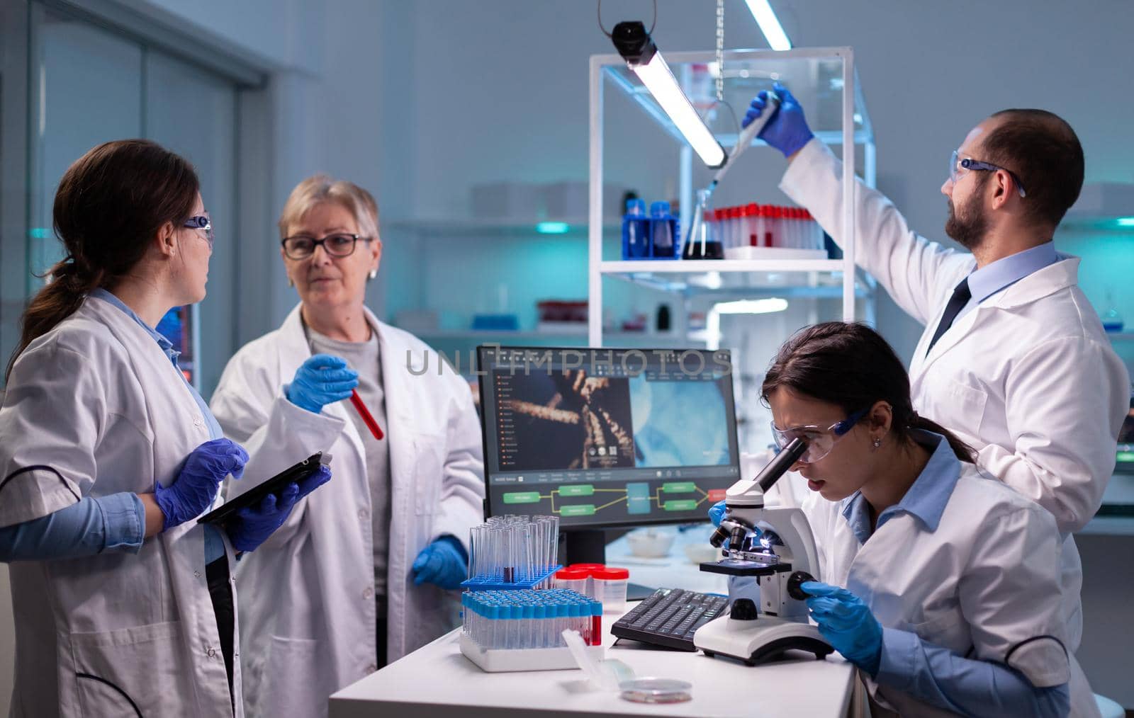 Woman tehnician lab doctor in white coat looking under microscope analysing various bacteria in laboratory. Research chemists working in lab with high tech examining genetic material samples