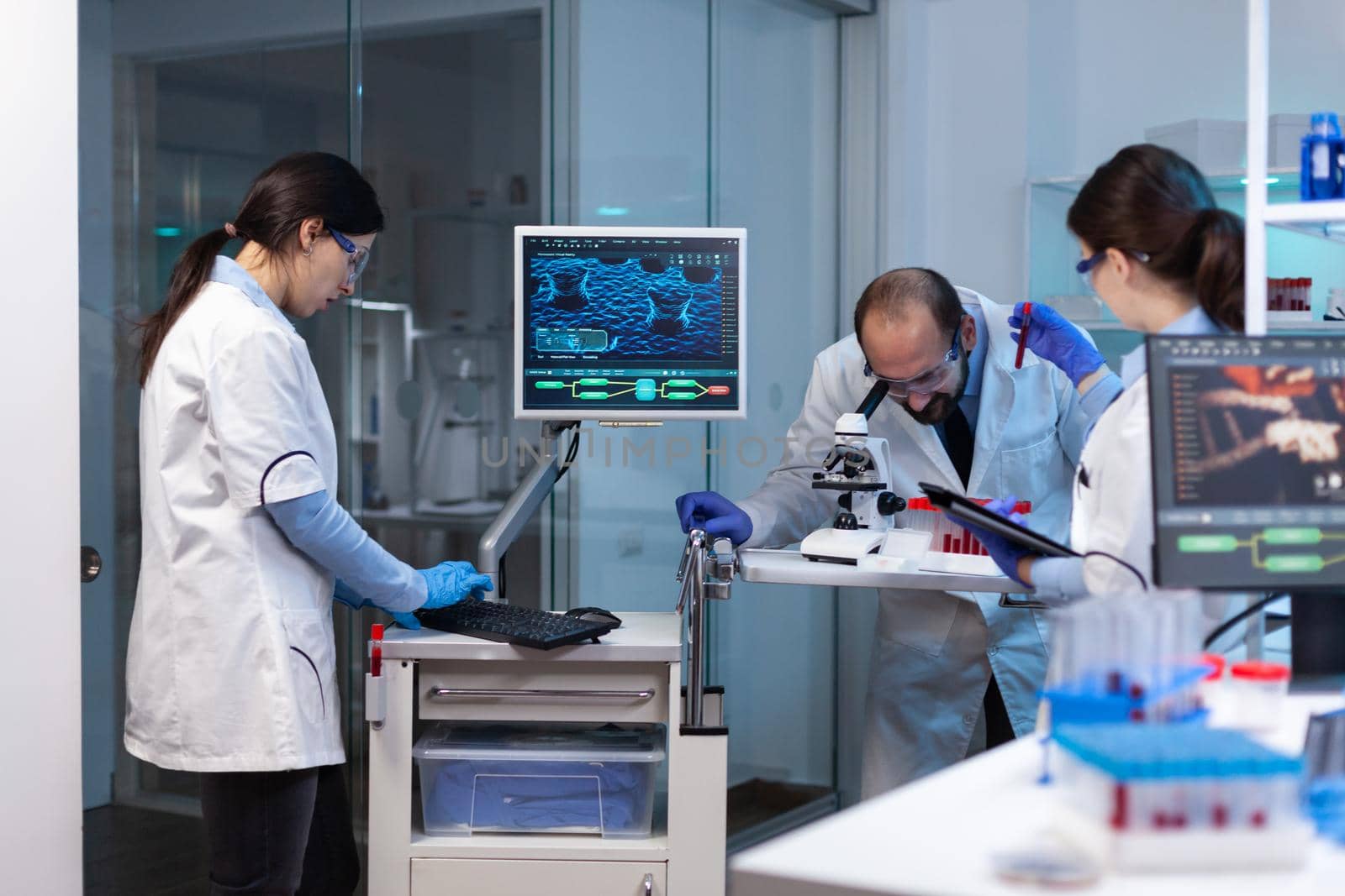 Group of scientists doing research and experiments at medical lab against disease with special equipment by DCStudio