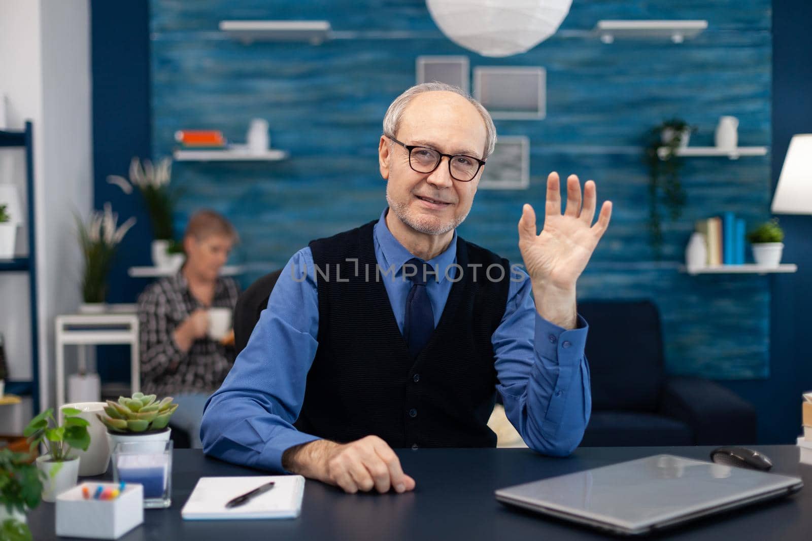 Senior businessman waving at camera by DCStudio