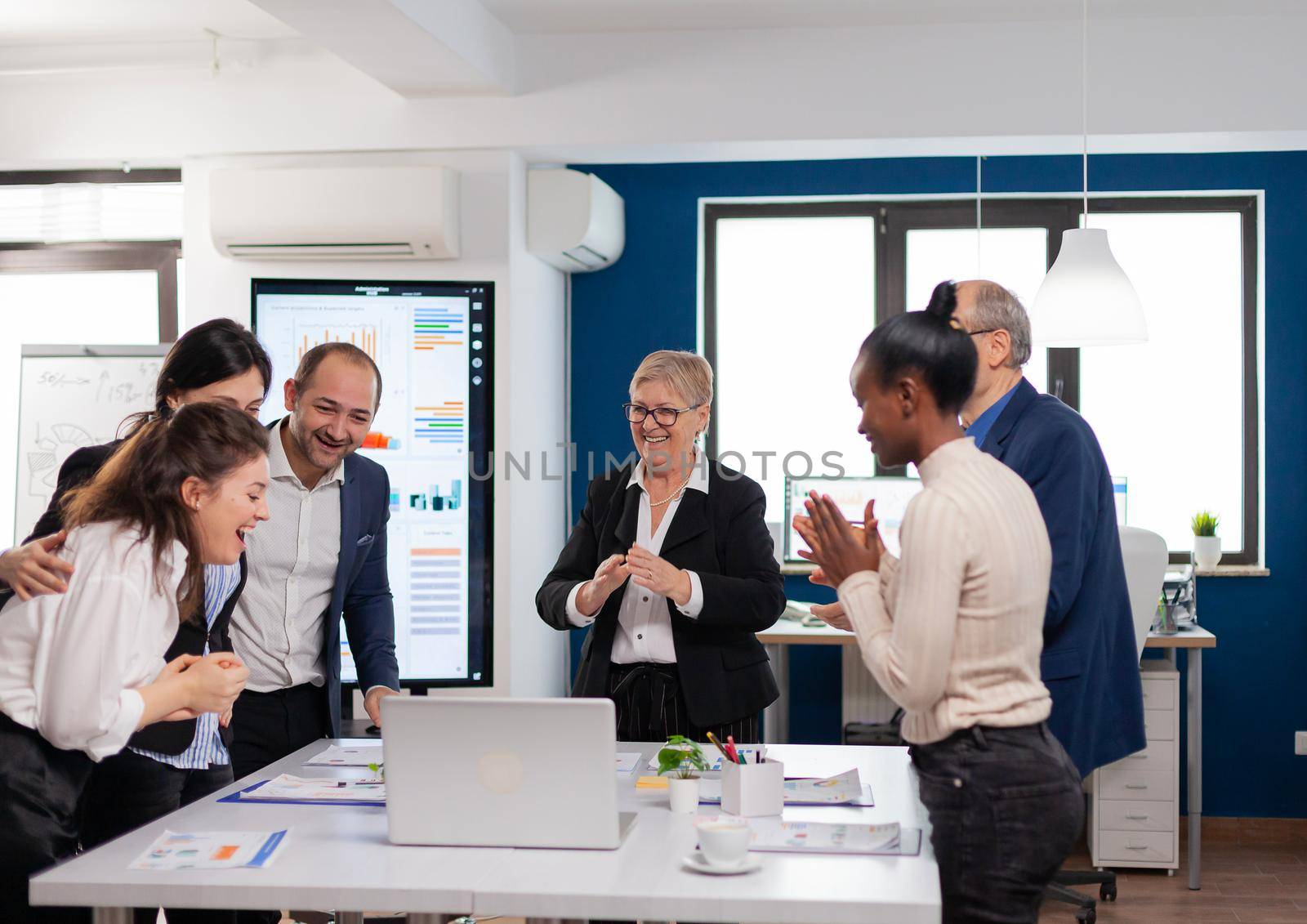 Management team clapping overjoyed in conference room after good training. Multiethnical partners coworkers celebrate successful teamwork result at company briefing