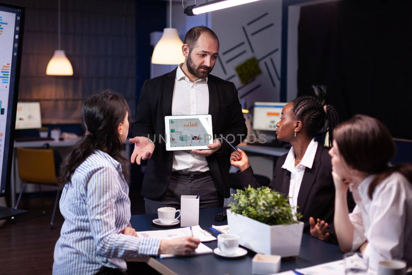 Overworked businessman showing financial graphs presentation using tablet by DCStudio