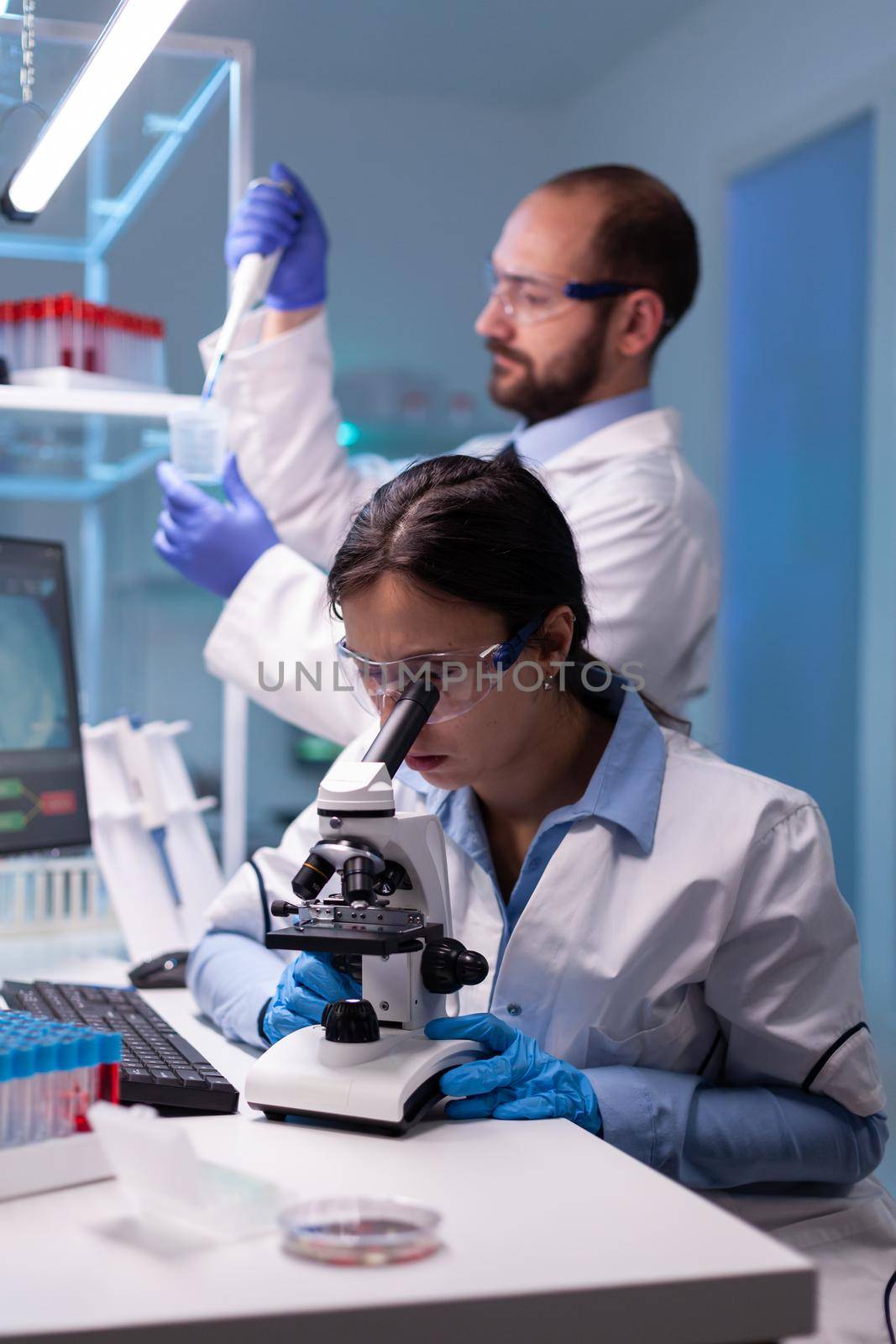 Chemist researchers working in laboratory with micropipette and microscope. Modern lab for scientific research with professional equipment for vaccine development diagnosing virus evolution.