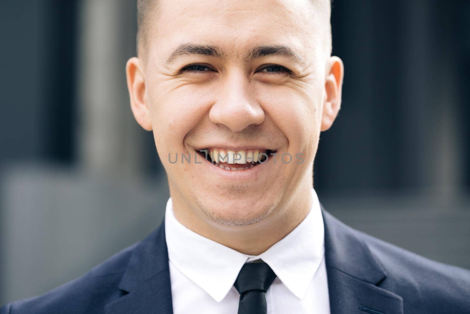 Portrait of handsome man in tie smiling cheerfully to camera at street near business center. Happy cheerful man looking straight with smile. Successful career attractive manager handsome confident.